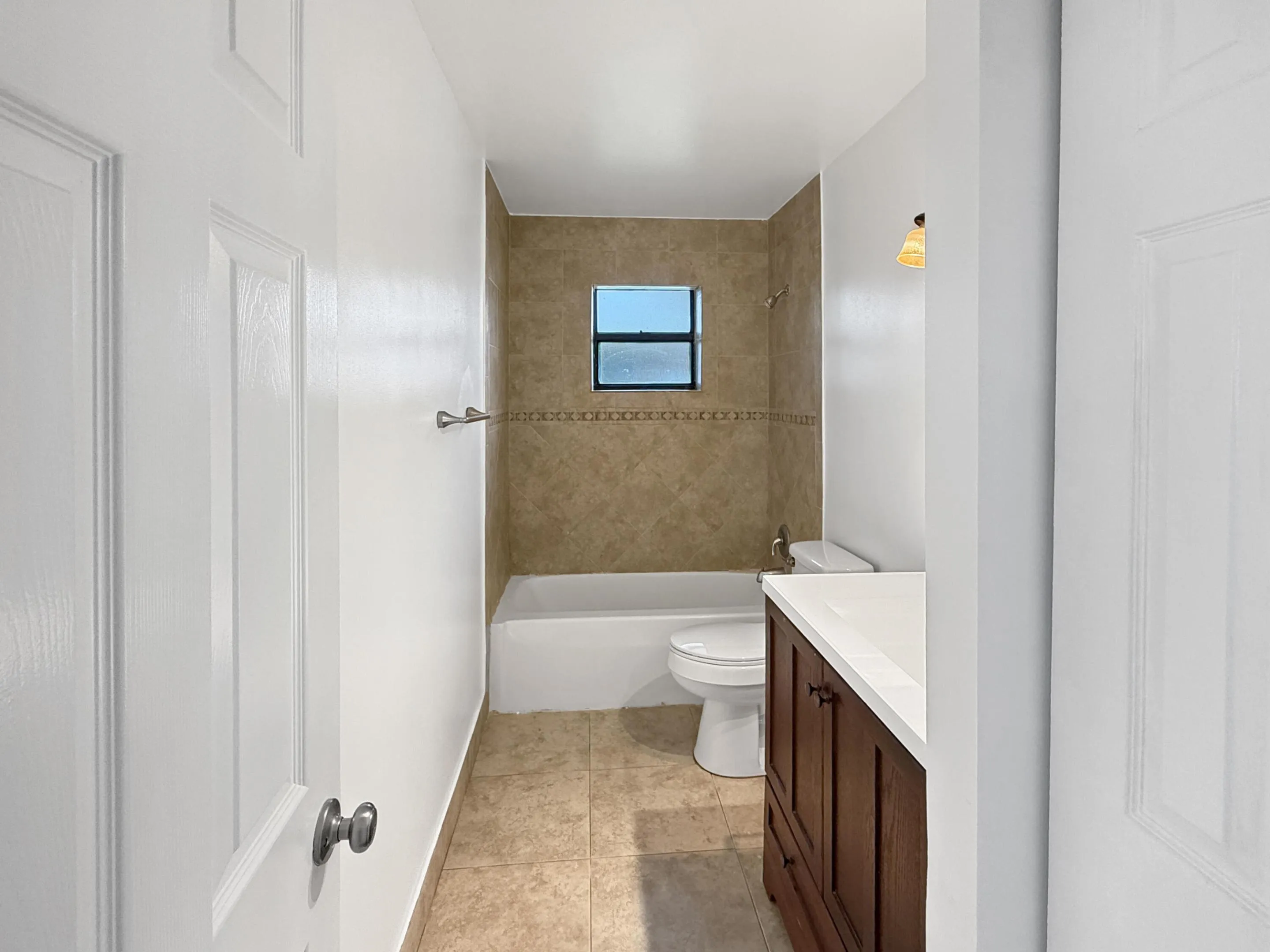 Tiled shower surround with decorative accent, built-in bathtub, and a window