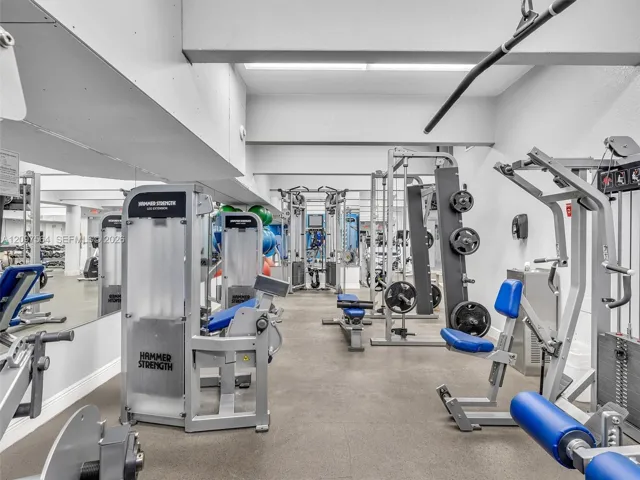 Dedicated fitness area featuring wall-to-wall mirrors, industrial-grade flooring, and structural ceiling beams