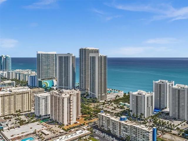 Aerial perspective of a coastal metropolitan area featuring high-rise developments, established hardscaping, and direct proximity to the ocean