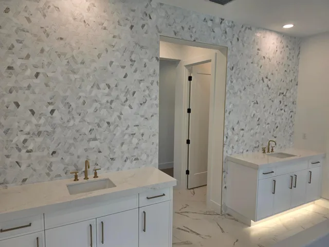 Primary Bathroom dual vanities with toe kick lighting and full decorative tile backsplash
