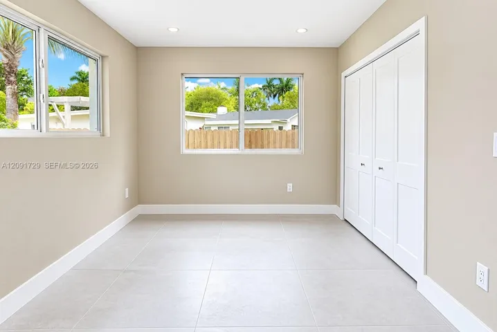 Neutral-toned interior featuring large-format tile flooring, recessed lighting, expansive windows, and a built-in double-panel closet