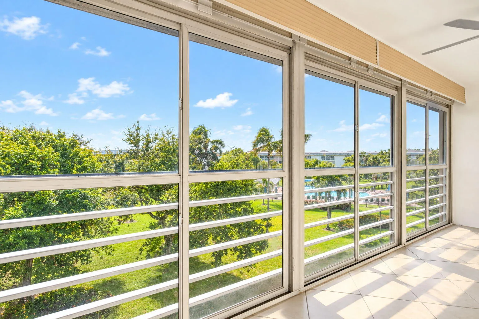 Sliding glass doors with a white frame, tile flooring, and ceiling fan