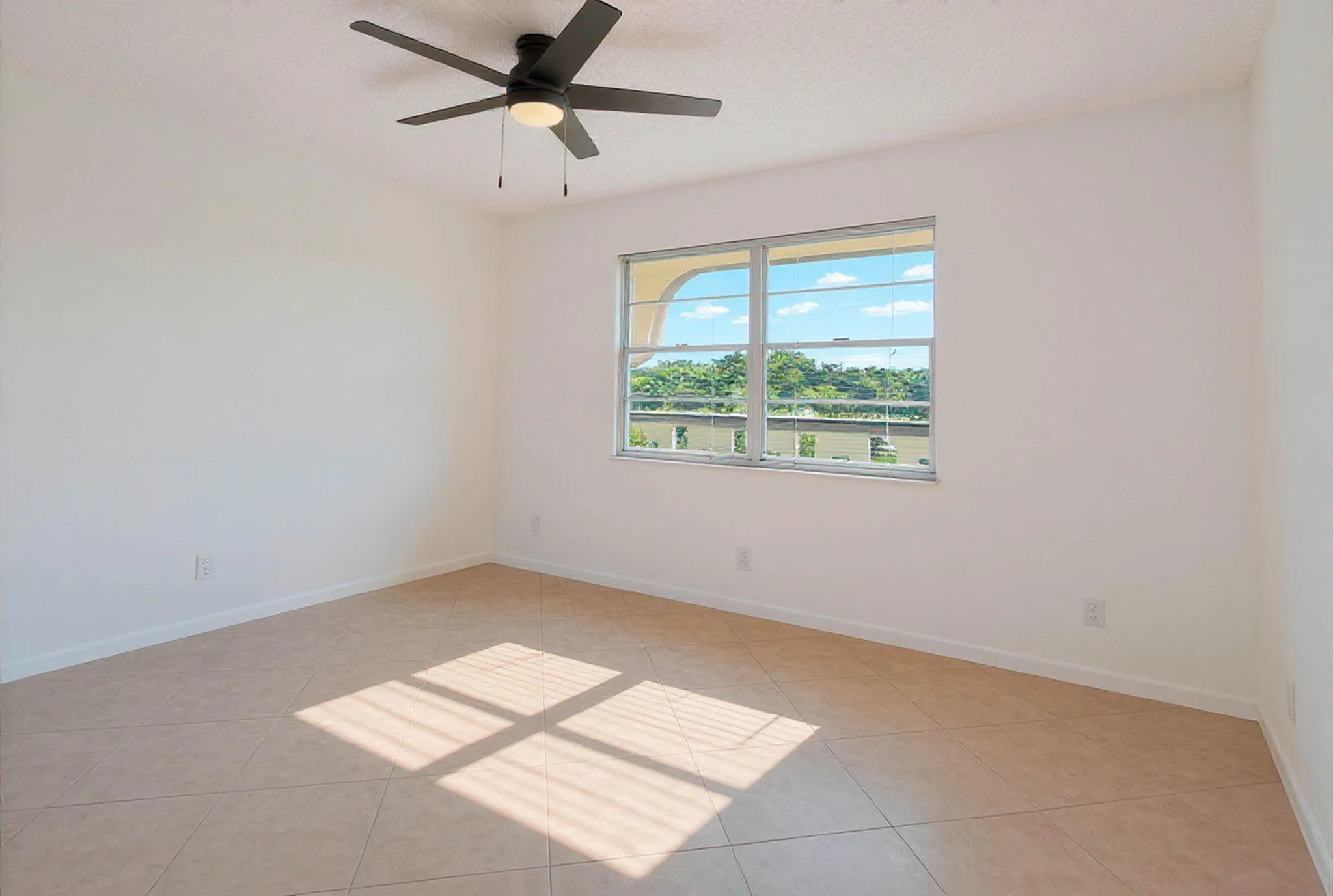 Room featuring a ceiling fan with integrated lighting, a large window with multiple panes, and tile flooring
