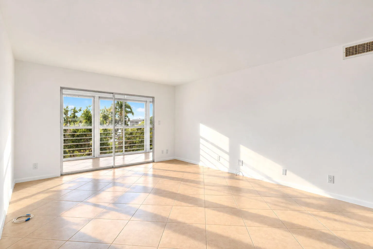 Sliding glass doors with a balcony railing, tile flooring, and white walls