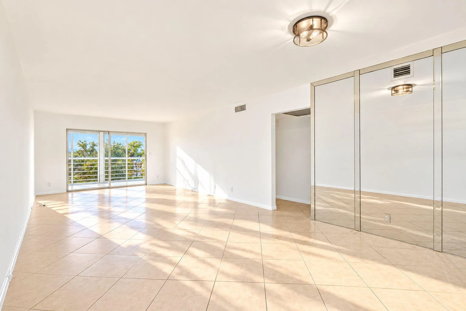 Expansive living area with large format tile flooring, white walls, and a contemporary flush-mount ceiling light