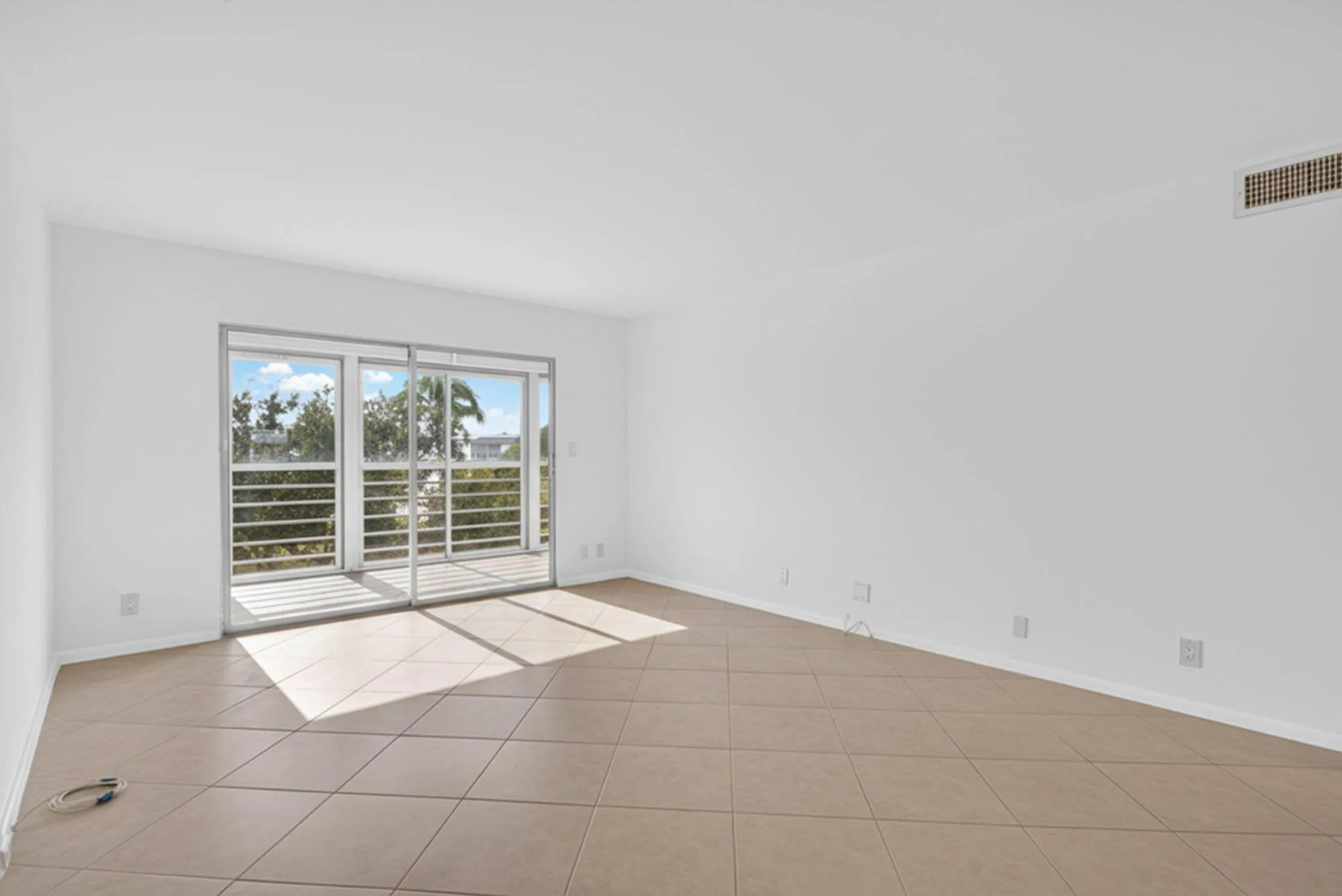 Slider door with a balcony, tile flooring, and white walls