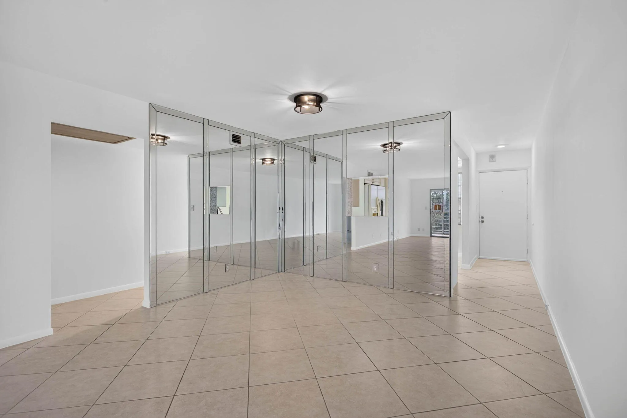Mirrored wall partition, recessed ceiling lighting, flush mount ceiling light fixtures, tile flooring, and white painted walls