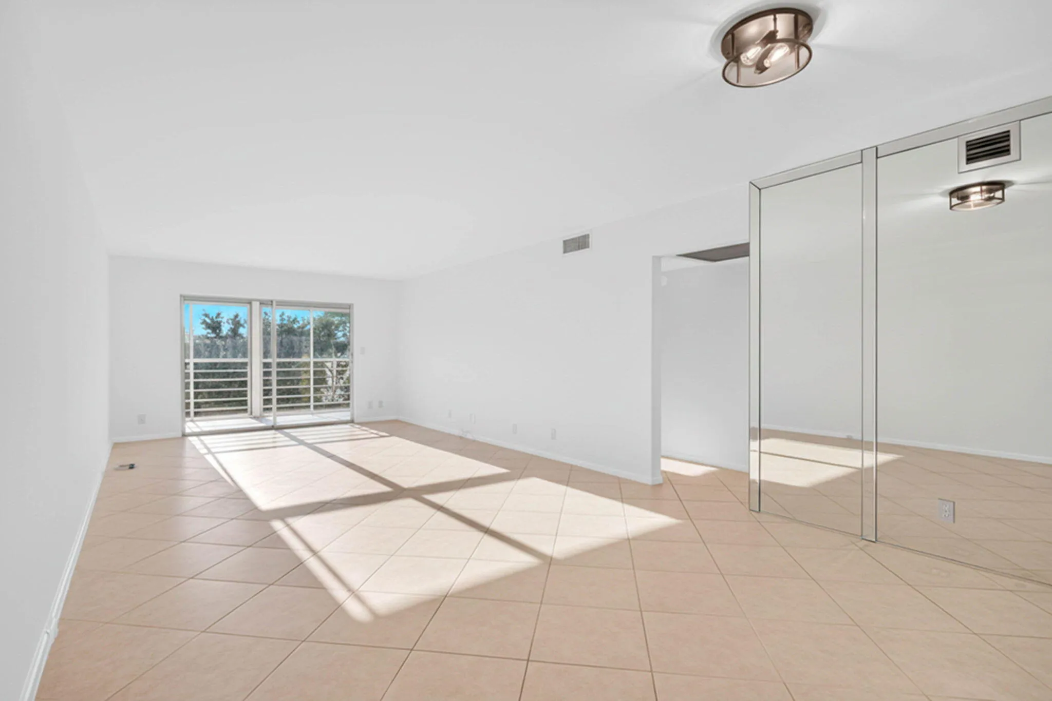 Sliding glass doors, tiled flooring, flush-mount lighting, and mirrored wall panels