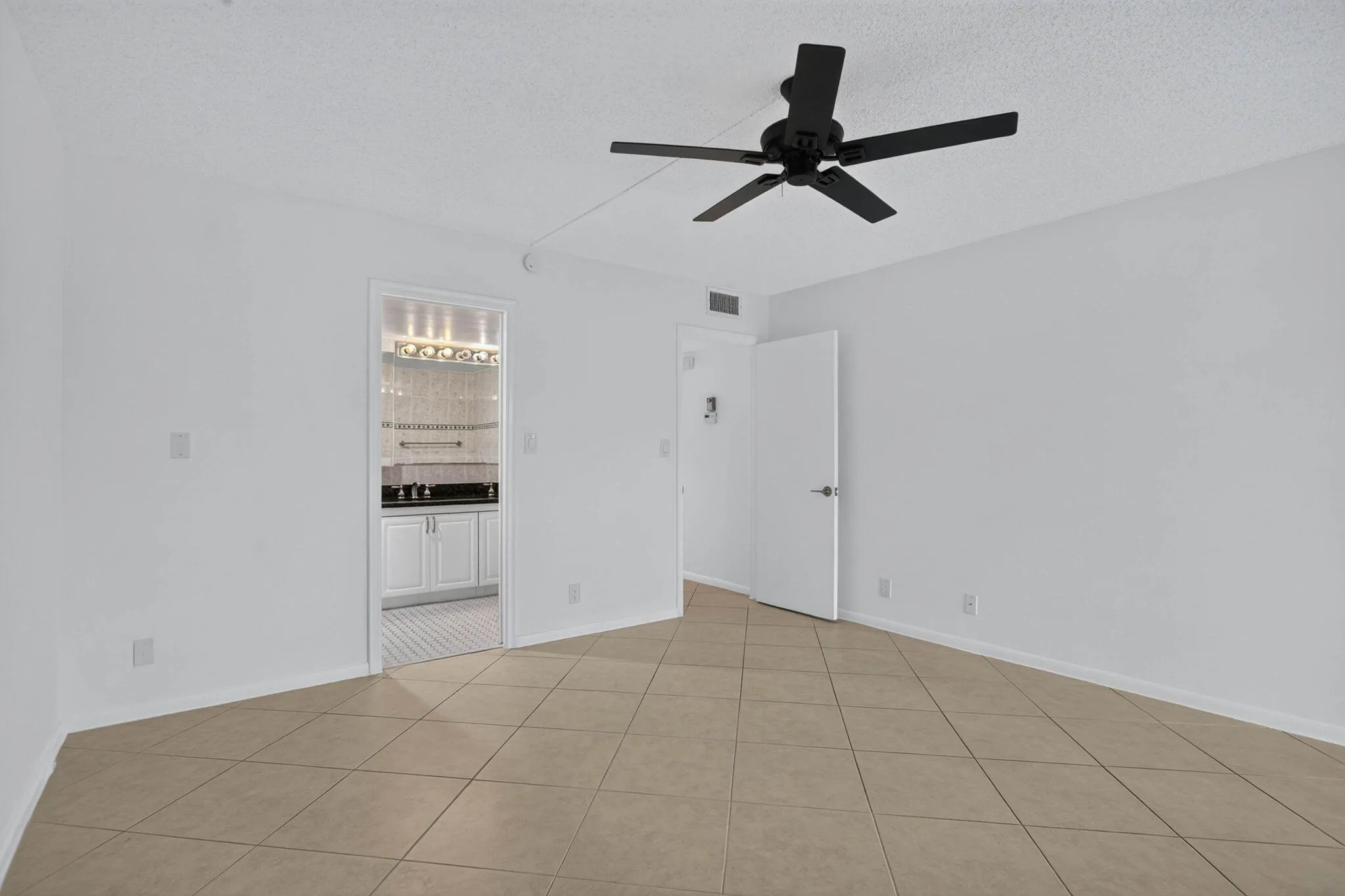 Neutral-toned tile flooring, white painted walls, and a matte black ceiling fan