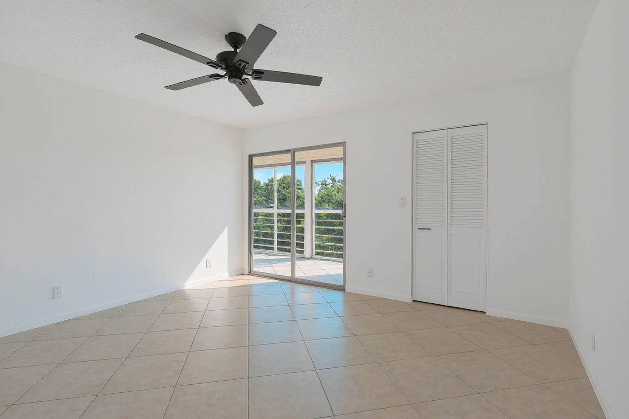Tile flooring, sliding glass door, balcony, louvered bi-fold closet doors, and ceiling fan