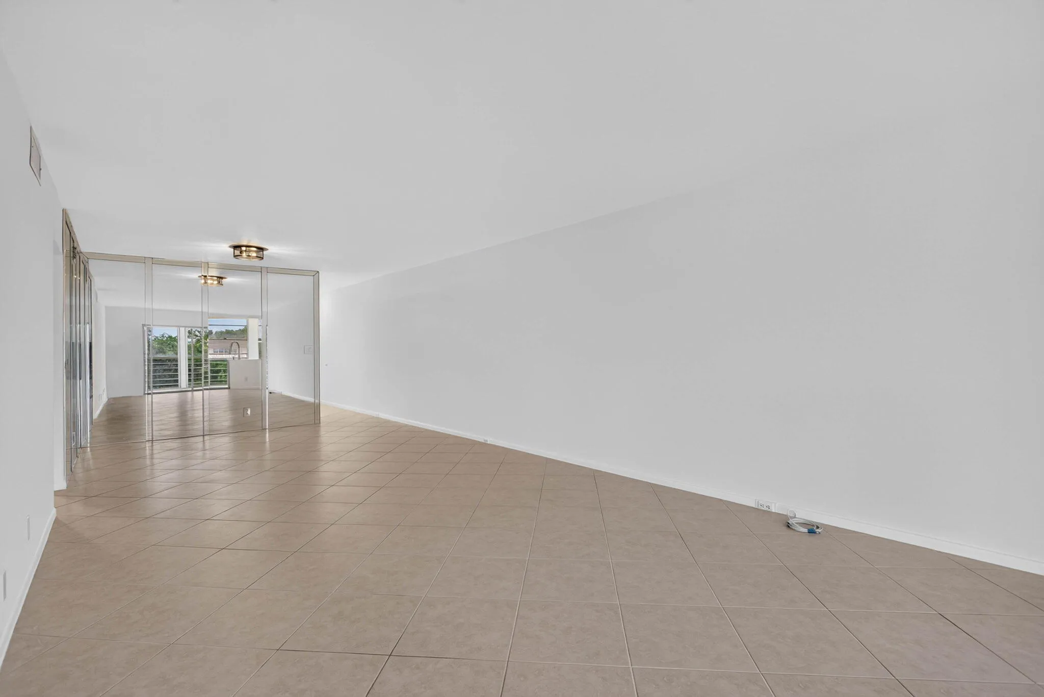 Spacious interior with tile flooring, white walls, and a mirrored wall feature