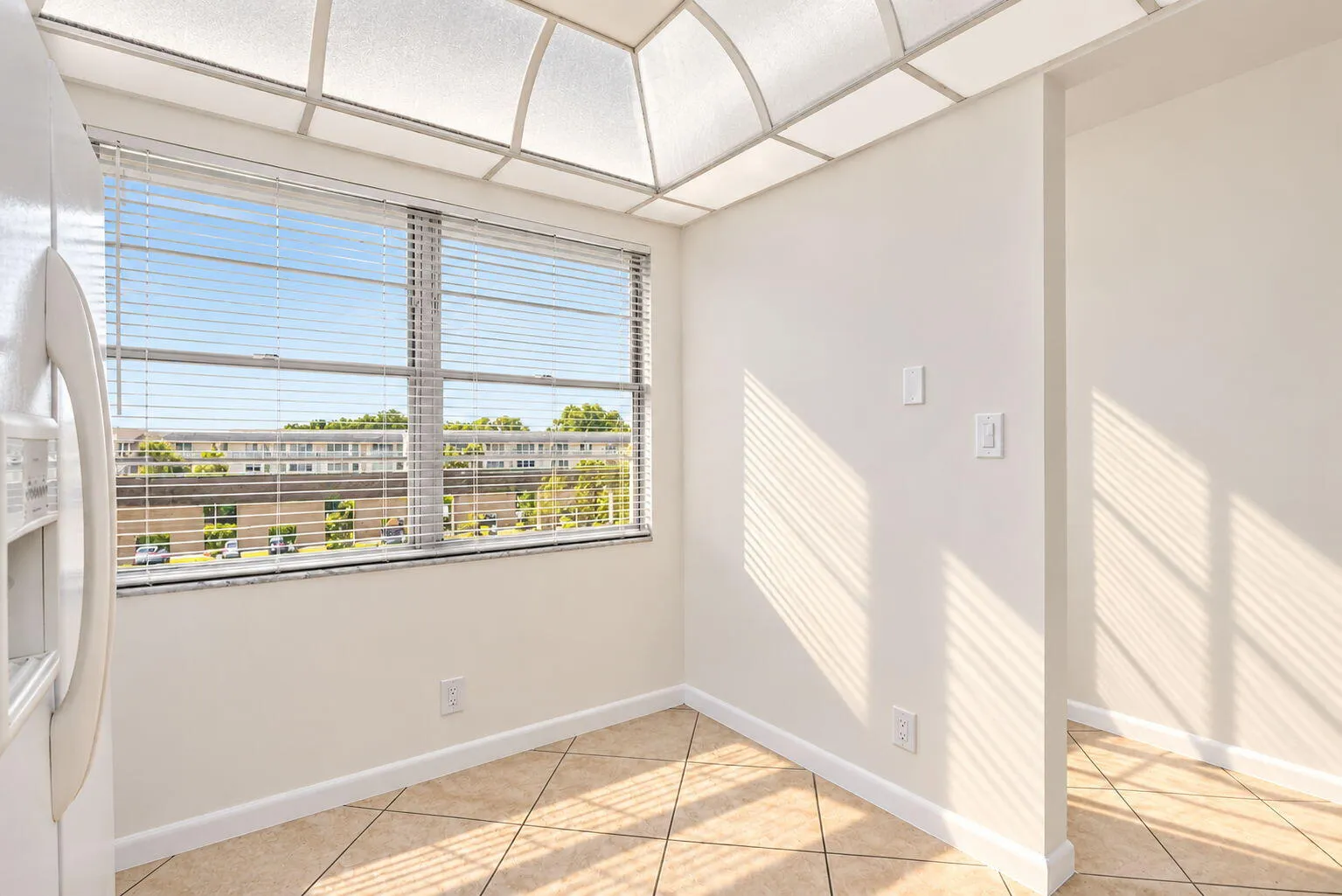 Large window with horizontal blinds, overhead grid ceiling lighting, and tiled flooring