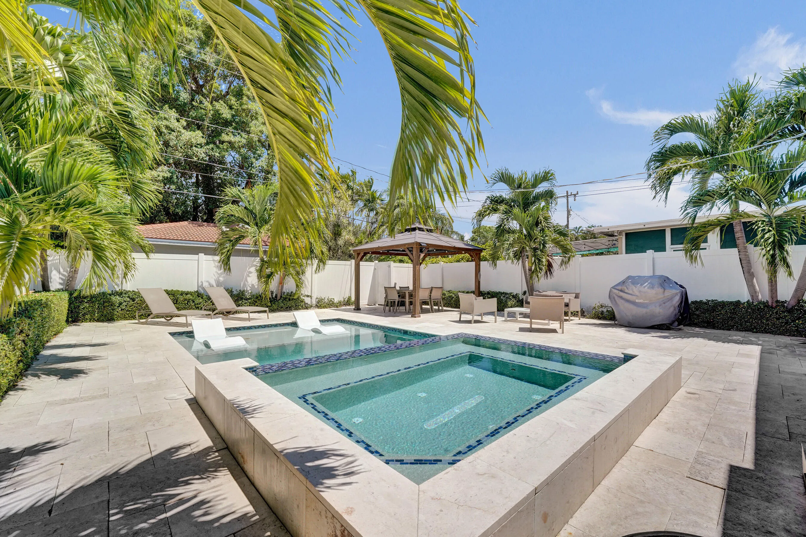 Travertine paver patio with a built-in swimming pool, integrated spa, and a gazebo