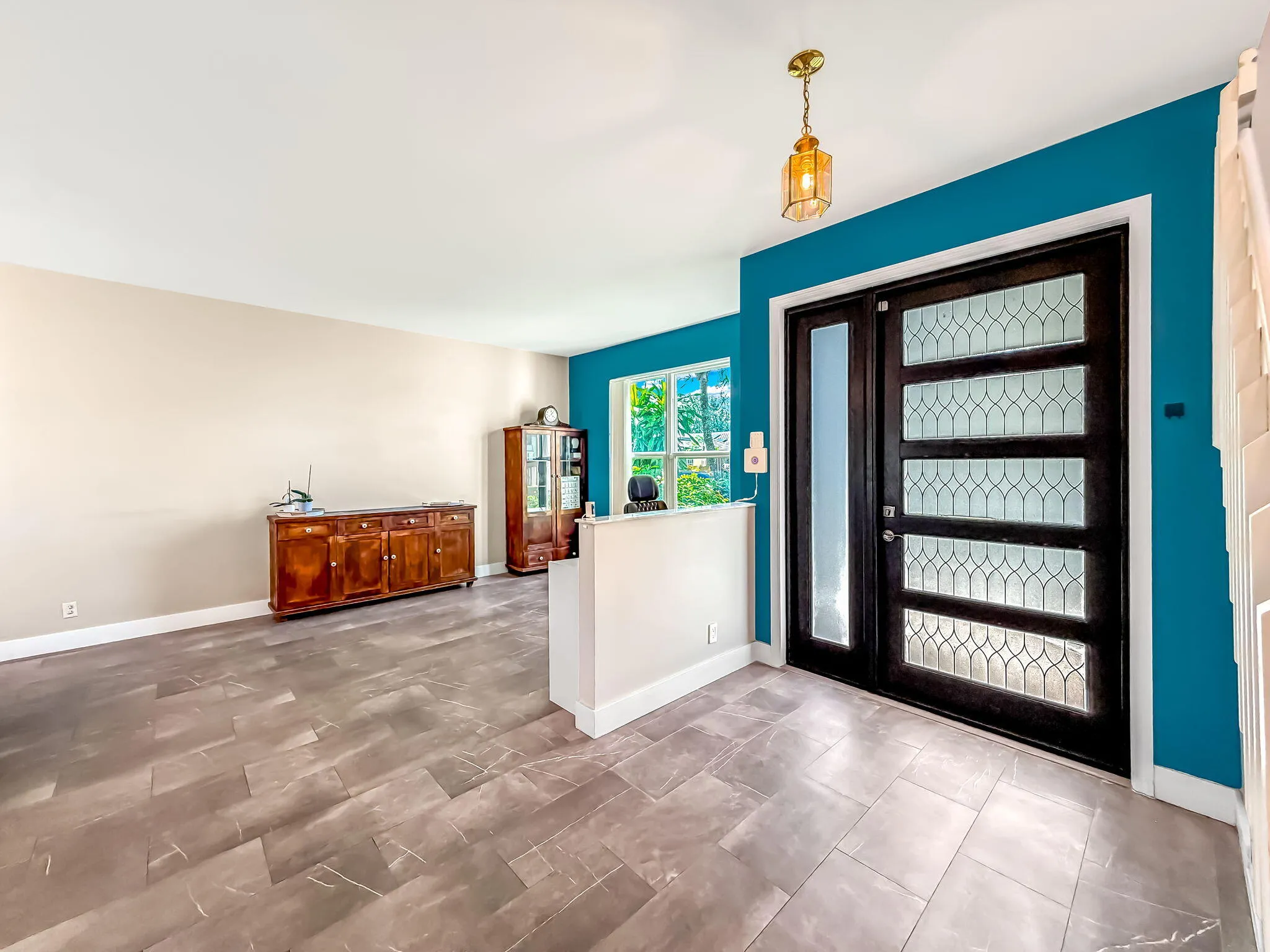 Entryway featuring a dark wood door with decorative glass panels, a side light, and a brass-tone pendant light