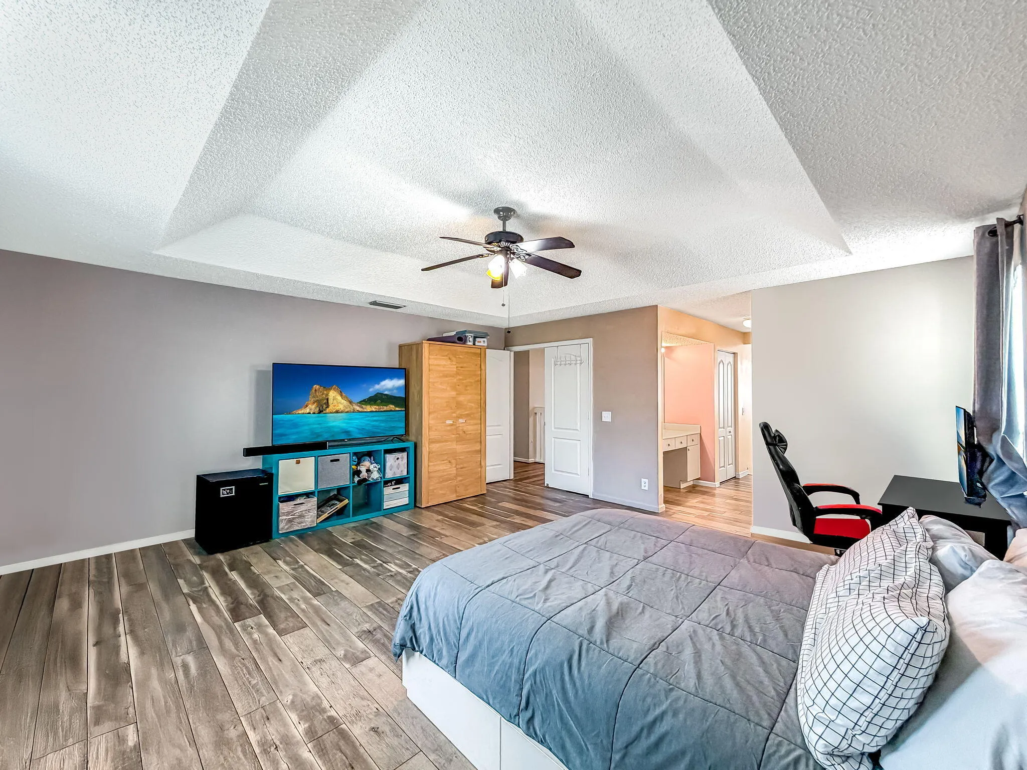 Vaulted ceiling with a ceiling fan, wood-finish flooring, and recessed built-in shelving