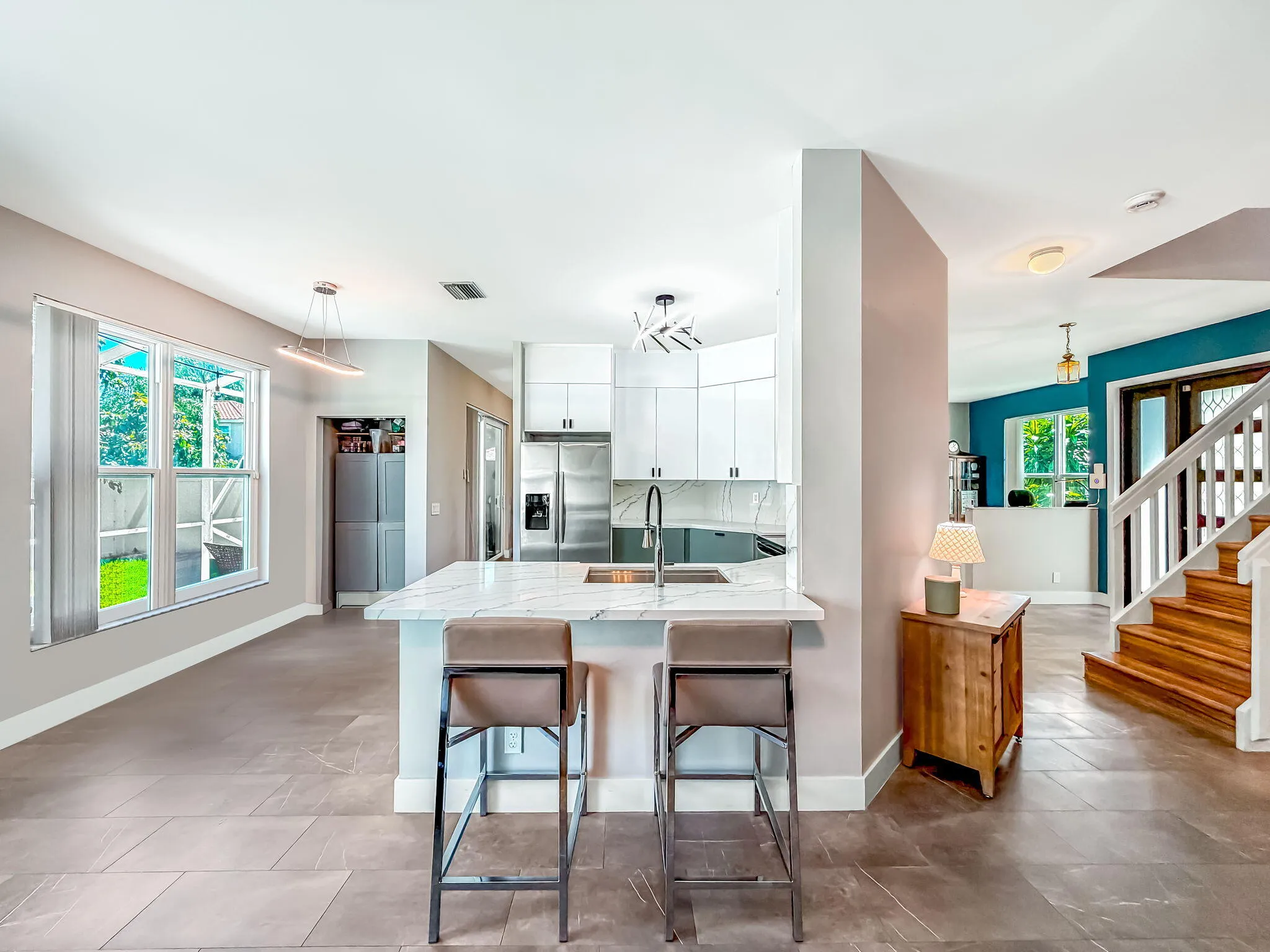 Modern kitchen with white cabinetry, stainless steel appliances, and a waterfall-edge island