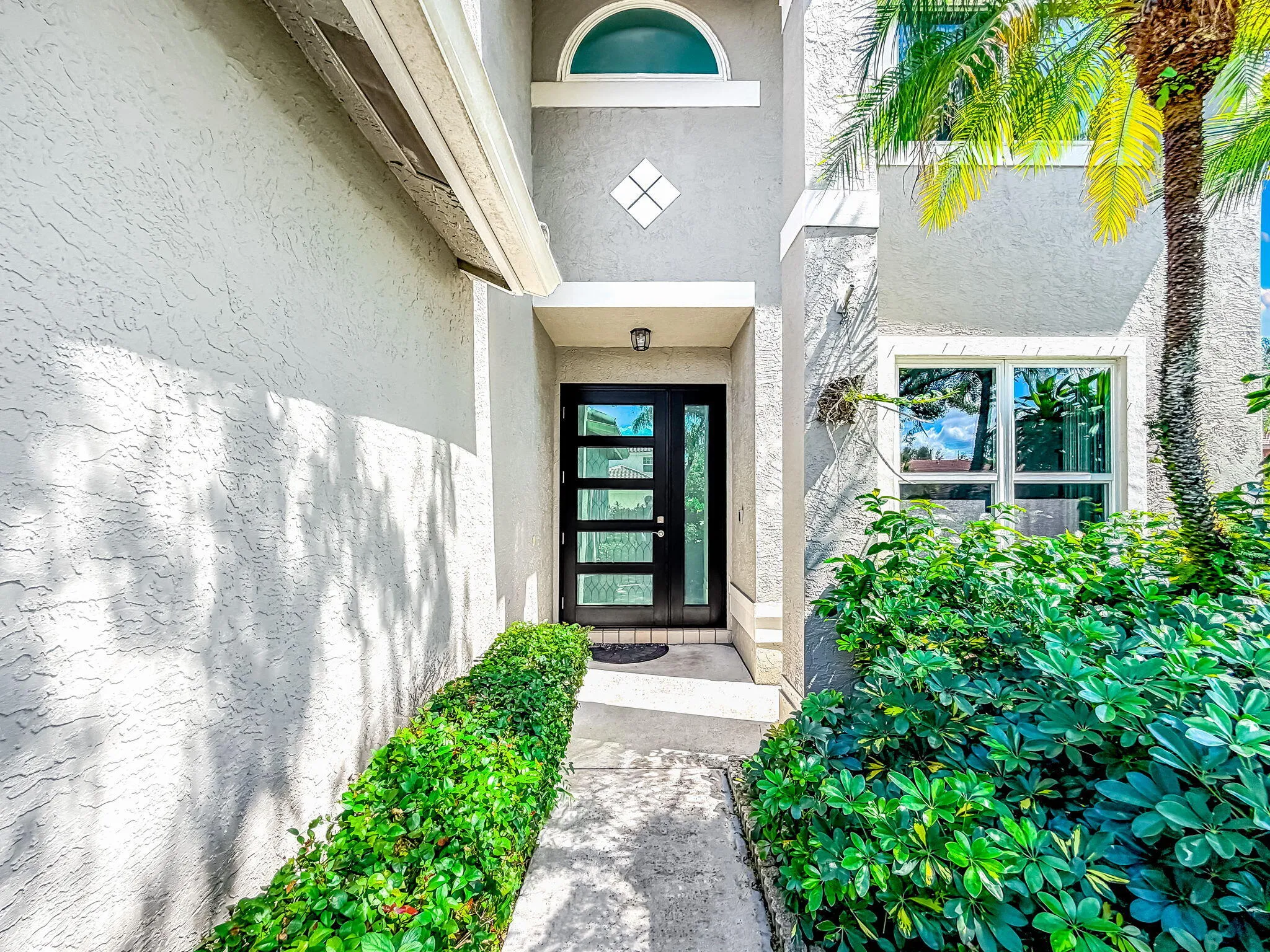 Modern entry door with horizontal glass panels, complemented by an arched transom window