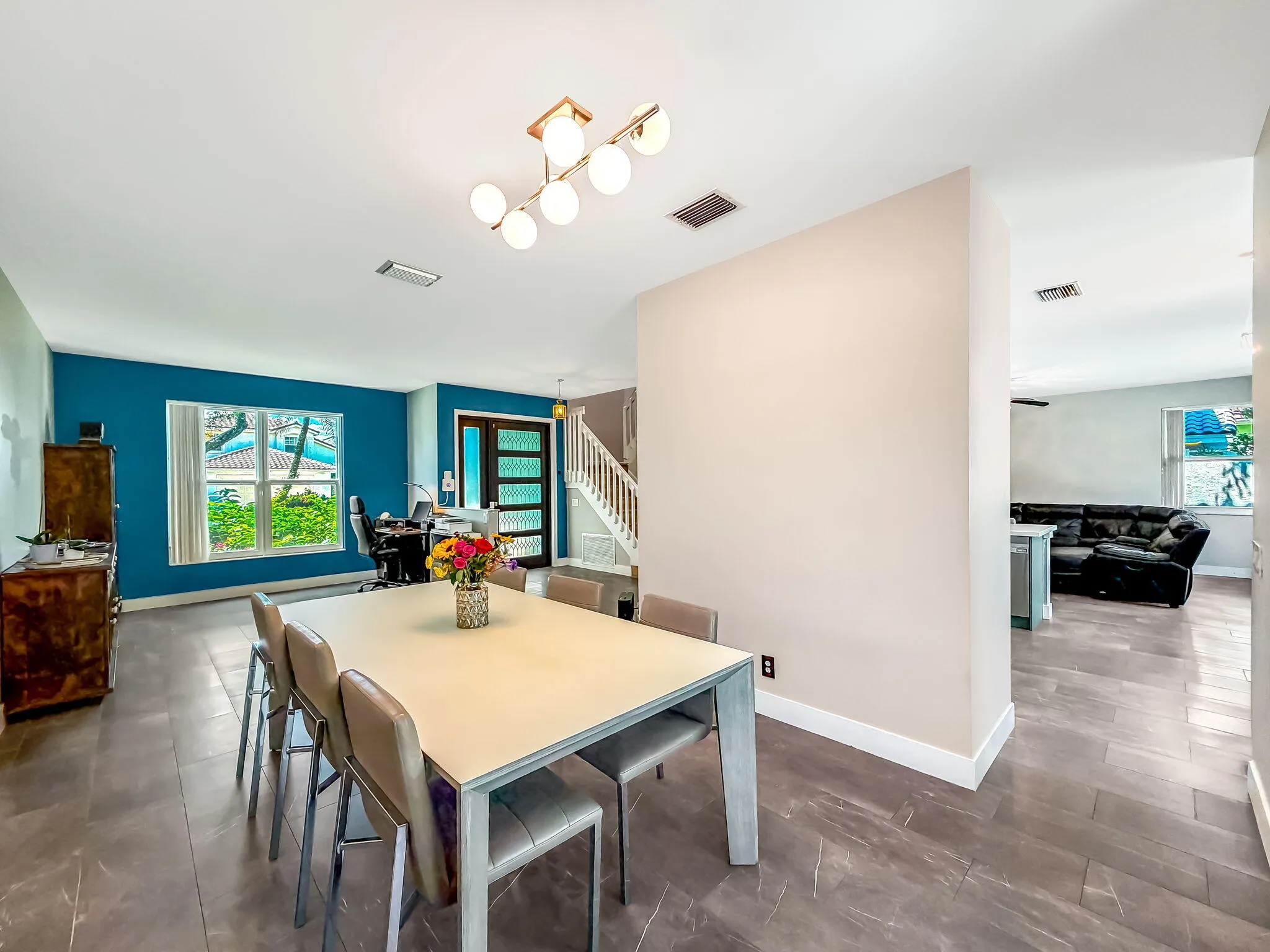 Open-concept dining area with large format tile flooring and a multi-bulb ceiling fixture