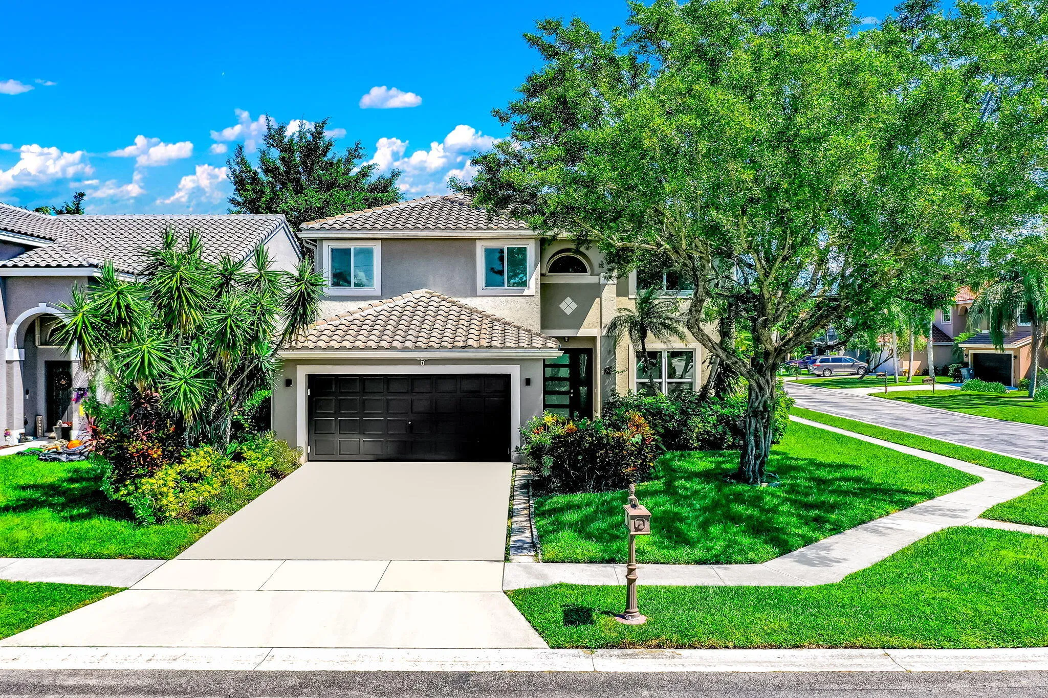 Two-story stucco exterior with a tiled roof, integrated garage, and a concrete driveway