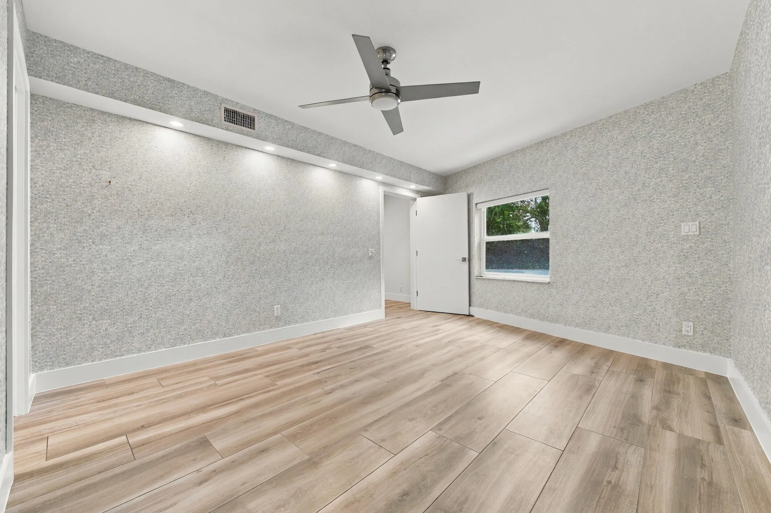 Wood-finish flooring, recessed lighting, ceiling fan, window, and textured wall finish