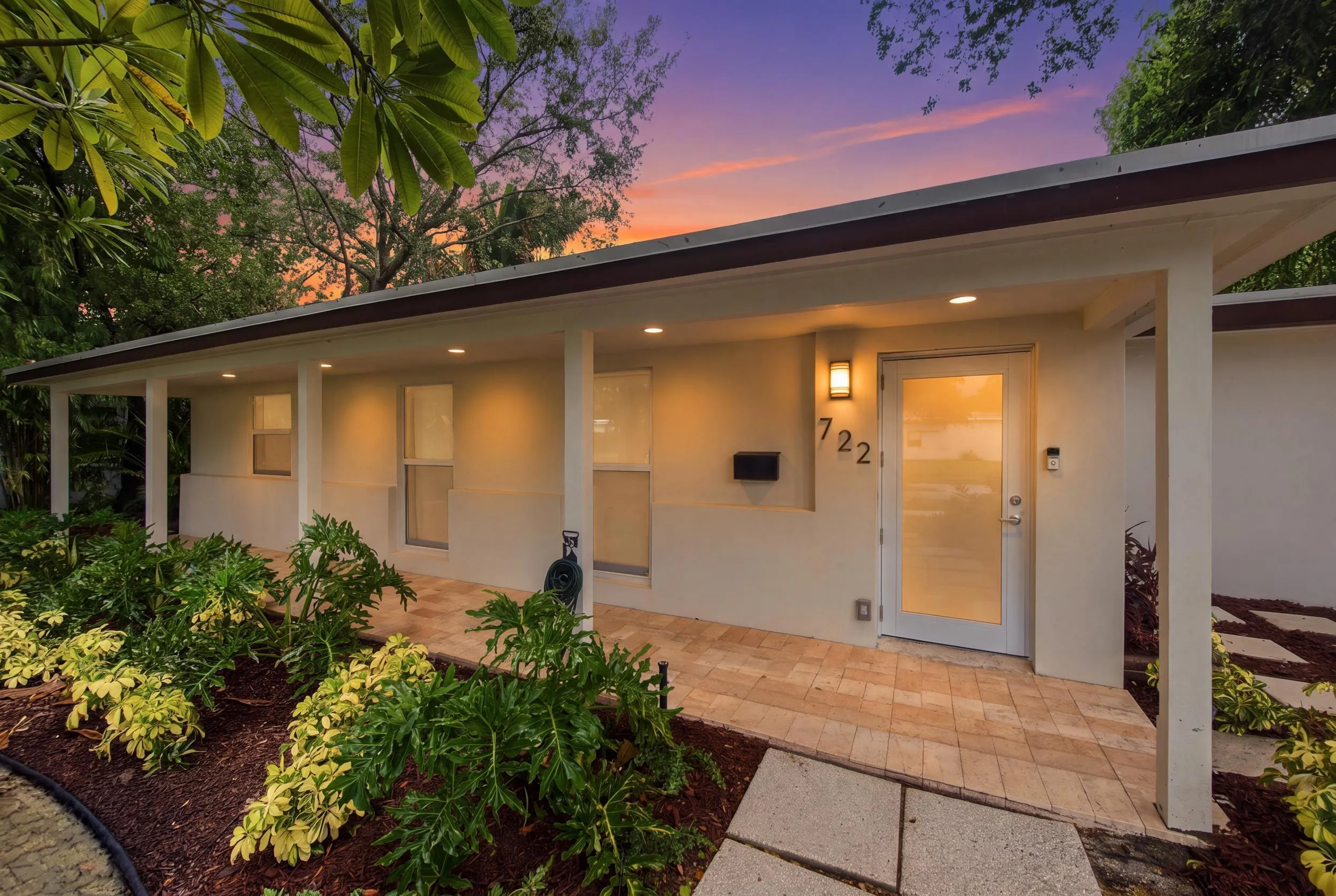 Exterior featuring a covered entry, recessed lighting, wall-mounted light fixture, decorative house numbers, and a frosted glass entry door