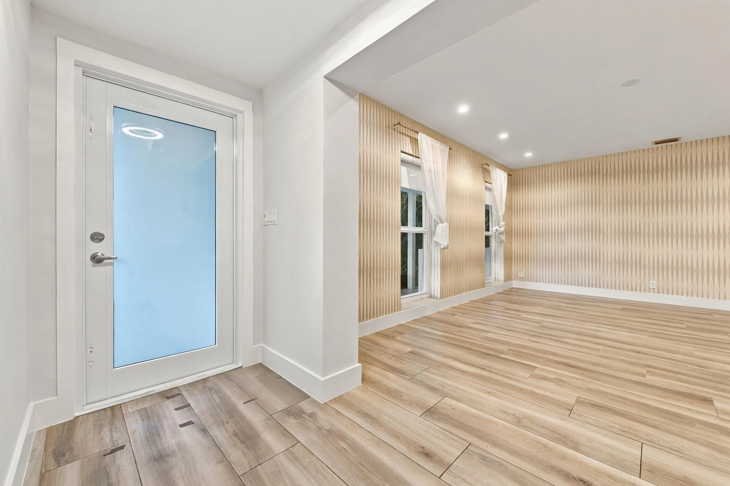 Full-light exterior door with frosted glass, recessed ceiling lighting, and wood-finish flooring