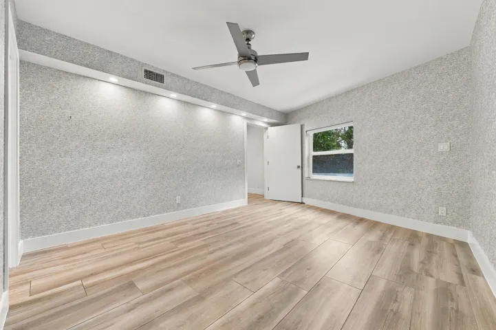 Wood-finish flooring, recessed lighting, ceiling fan, window, and textured wall finish