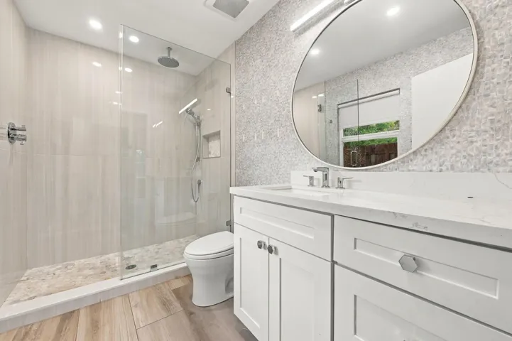 Glass-enclosed shower with a rainfall showerhead, integrated niche, and pebble-style flooring