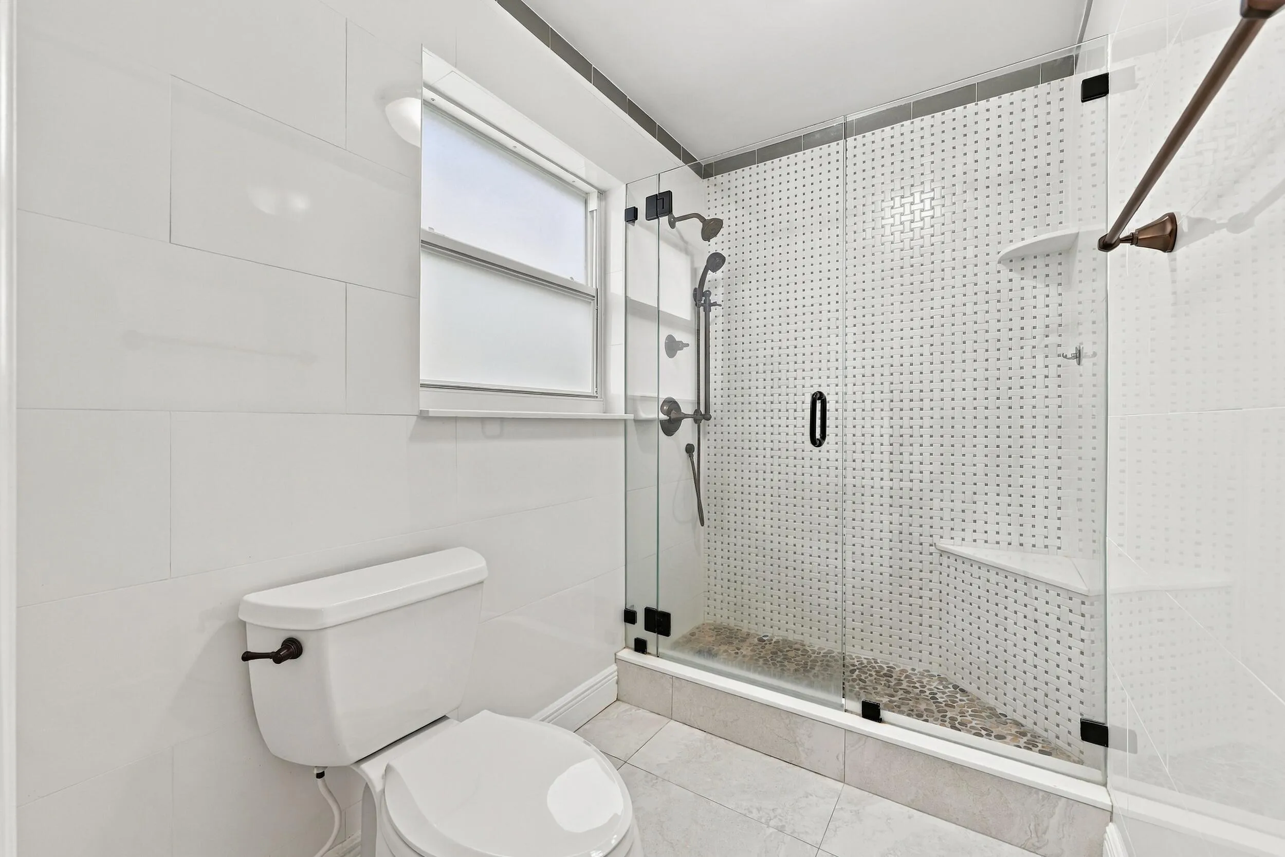 The fully renovated primary bathroom offers dual sinks, updated cabinetry, and a brand-new frameless glass shower.