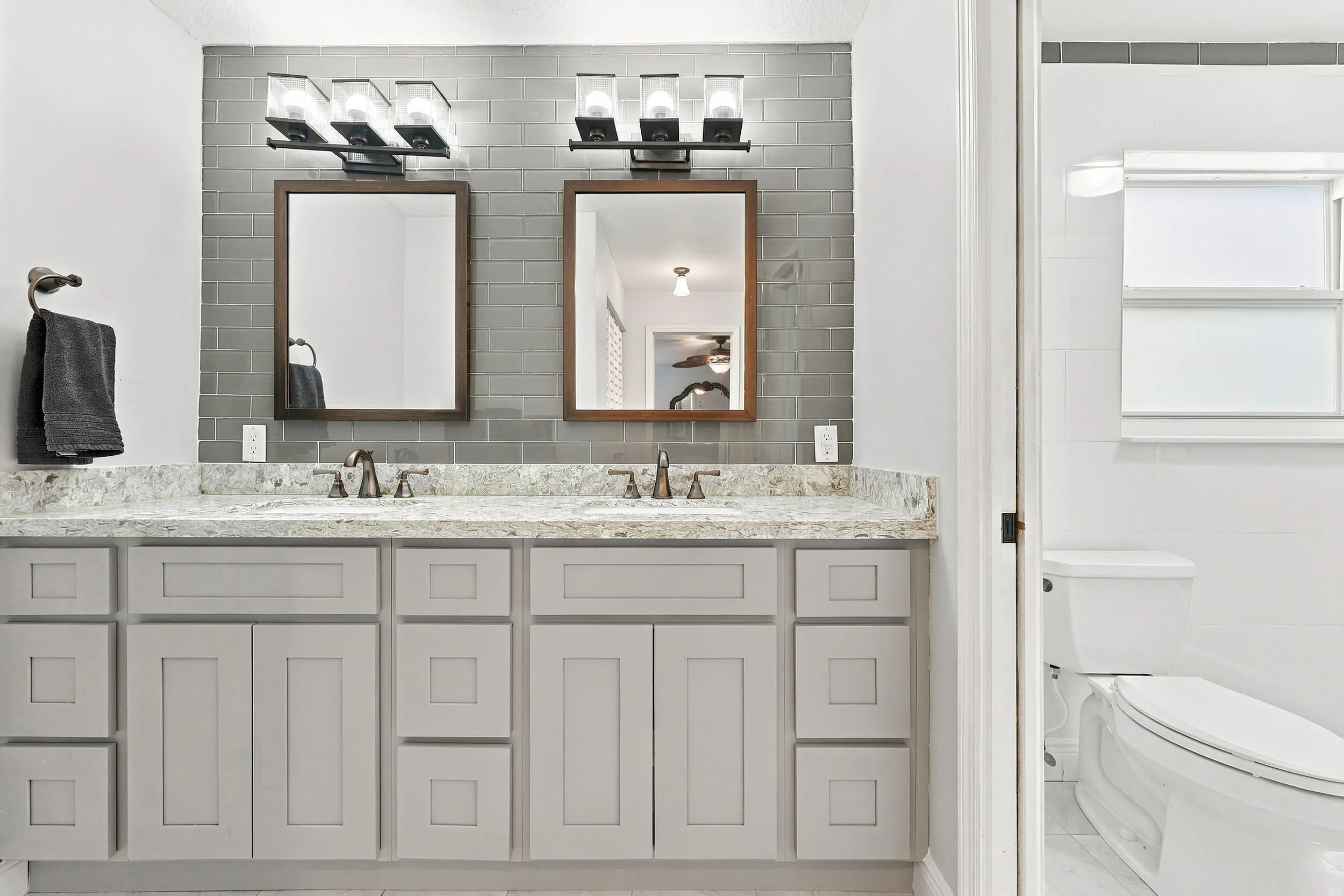 The fully renovated primary bathroom offers dual sinks, updated cabinetry, and a brand-new frameless glass shower.