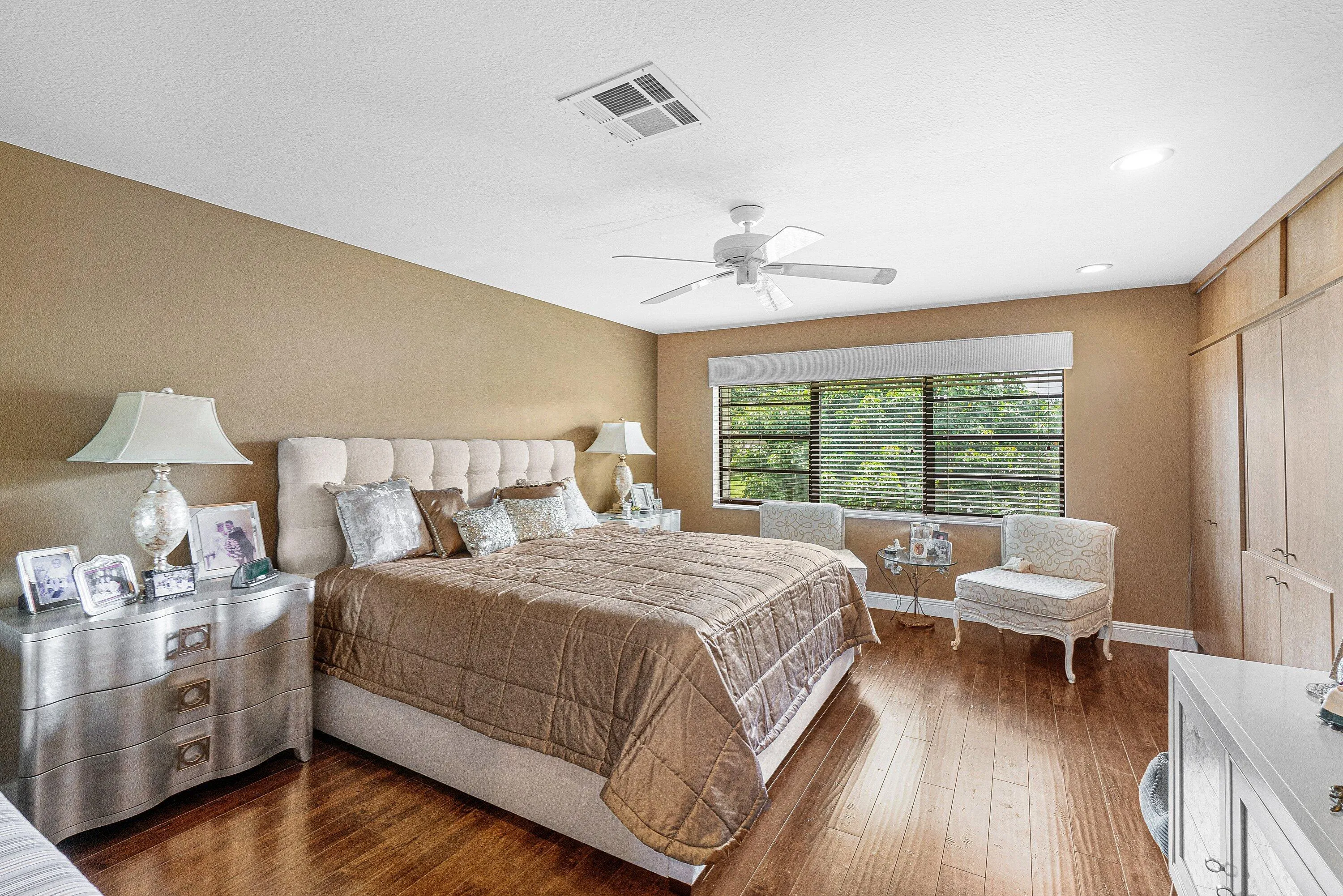 Wood-finish flooring, built-in cabinetry, ceiling fan, recessed lighting, and a large window with horizontal blinds