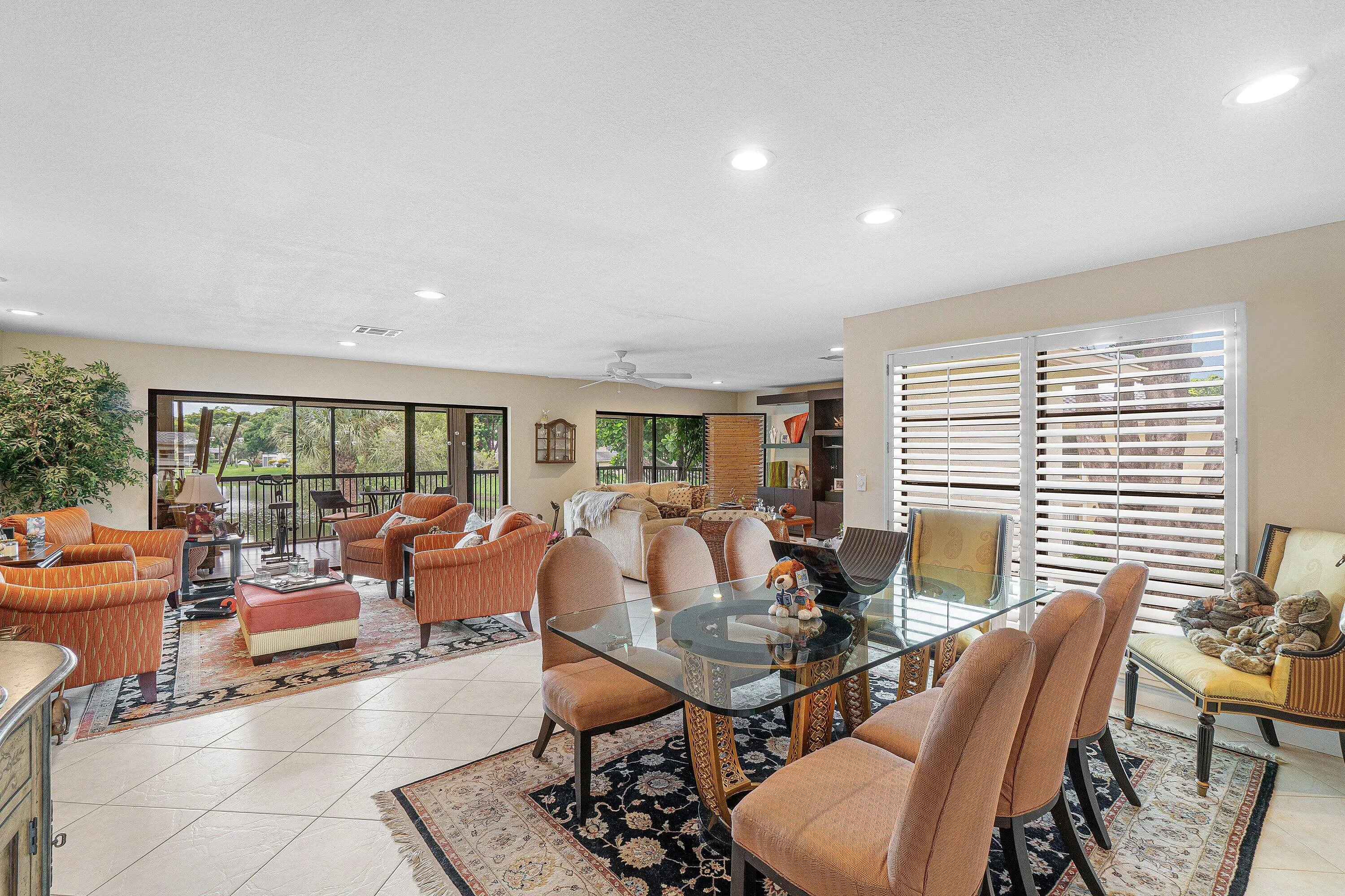 Open-concept living space with tile flooring, recessed lighting, and a glass-top dining table