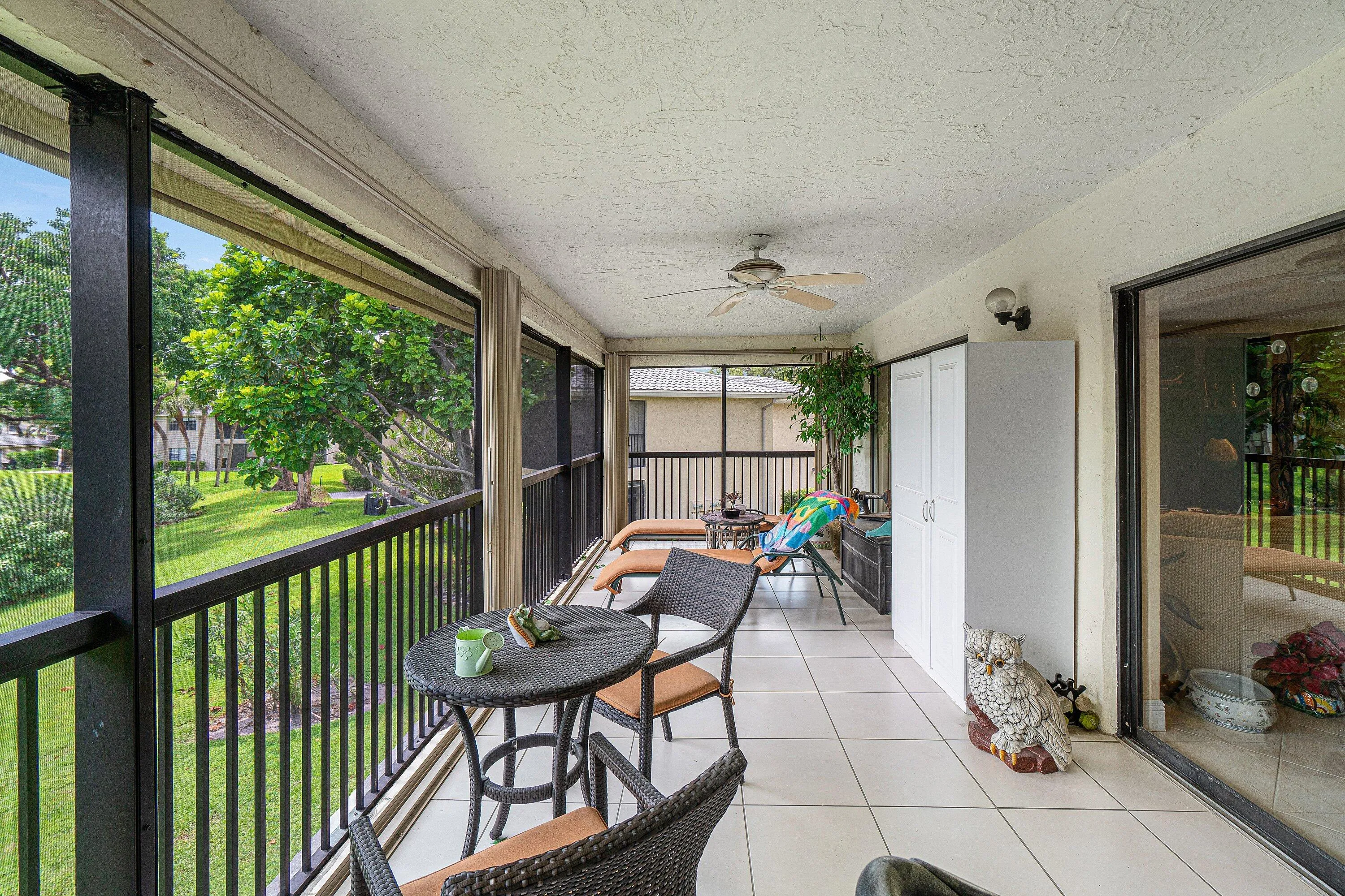 Screened lanai featuring large format tile flooring, a ceiling fan, and sliding glass door access
