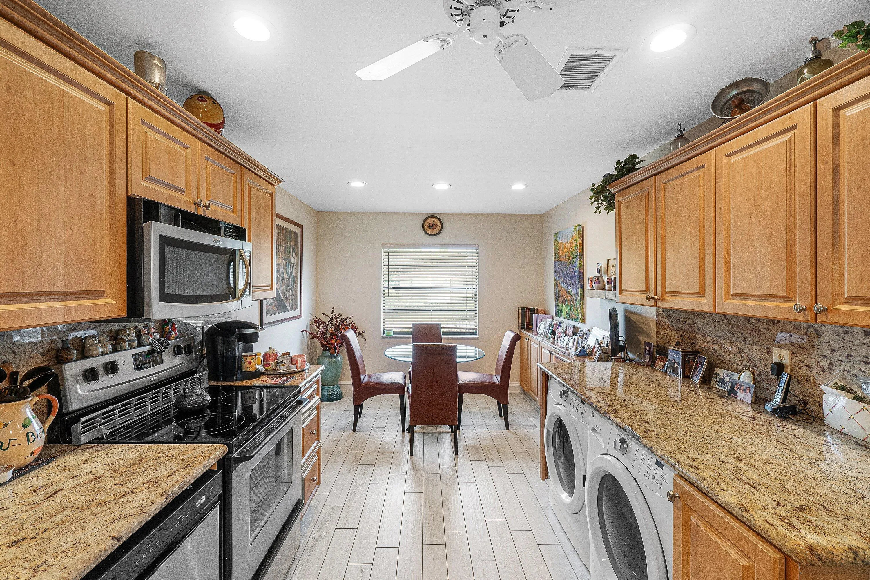 Kitchen featuring wood-finish cabinetry, granite-style countertops, stainless steel appliances, recessed lighting, and wood-look plank flooring