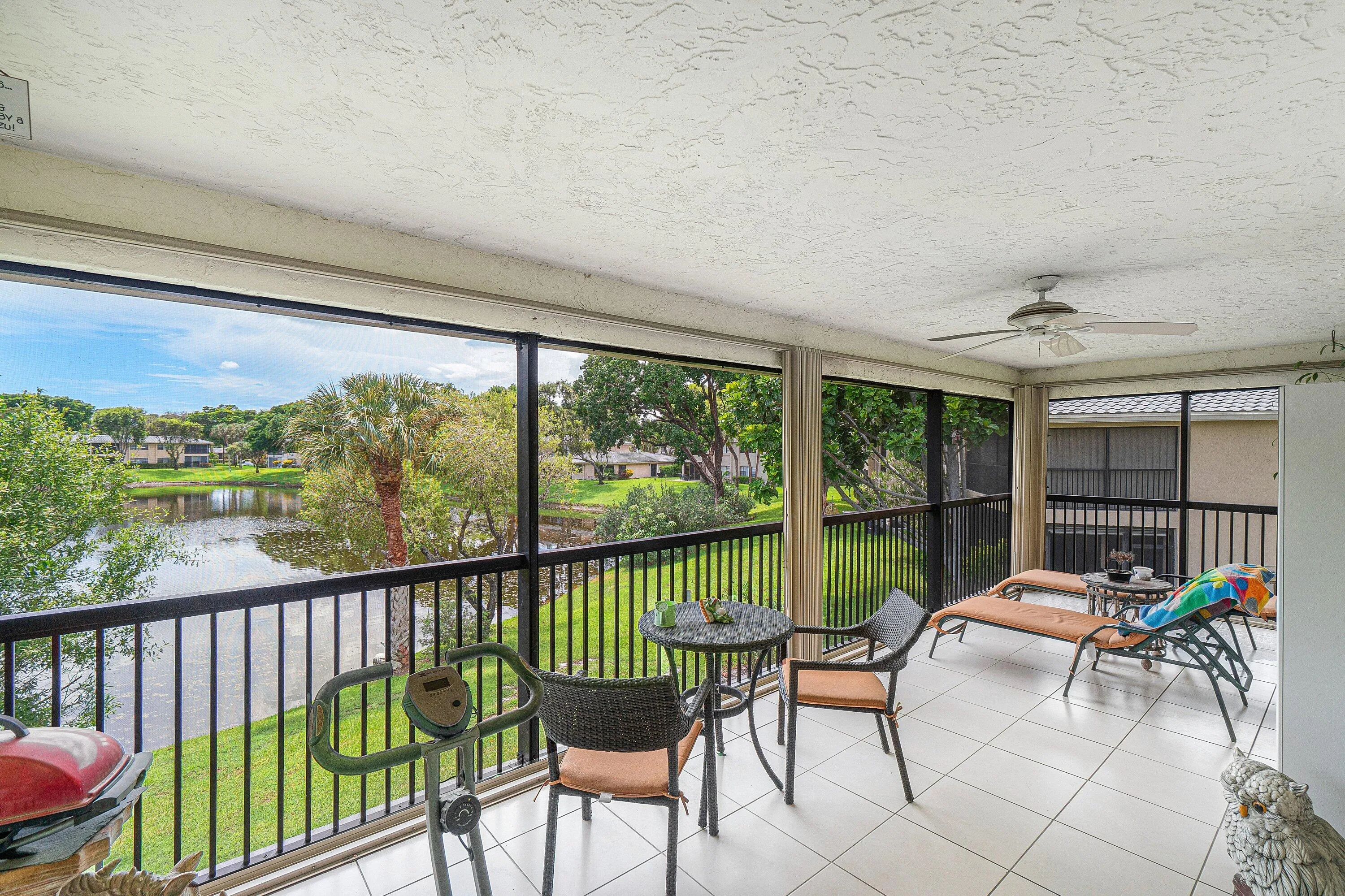 Screened balcony with tile flooring, ceiling fan, and metal railings