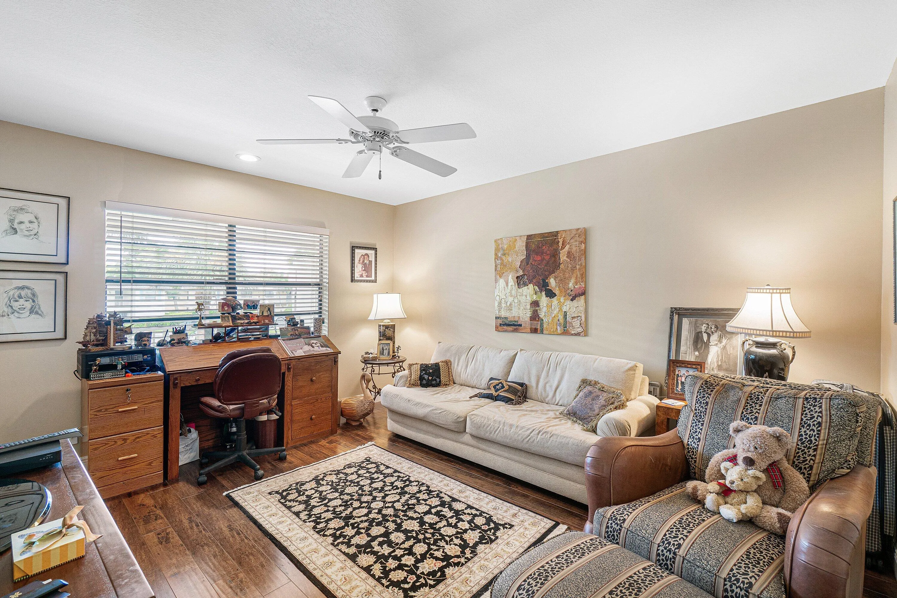 Wood-finish flooring, ceiling fan with integrated lighting, and window with horizontal blinds