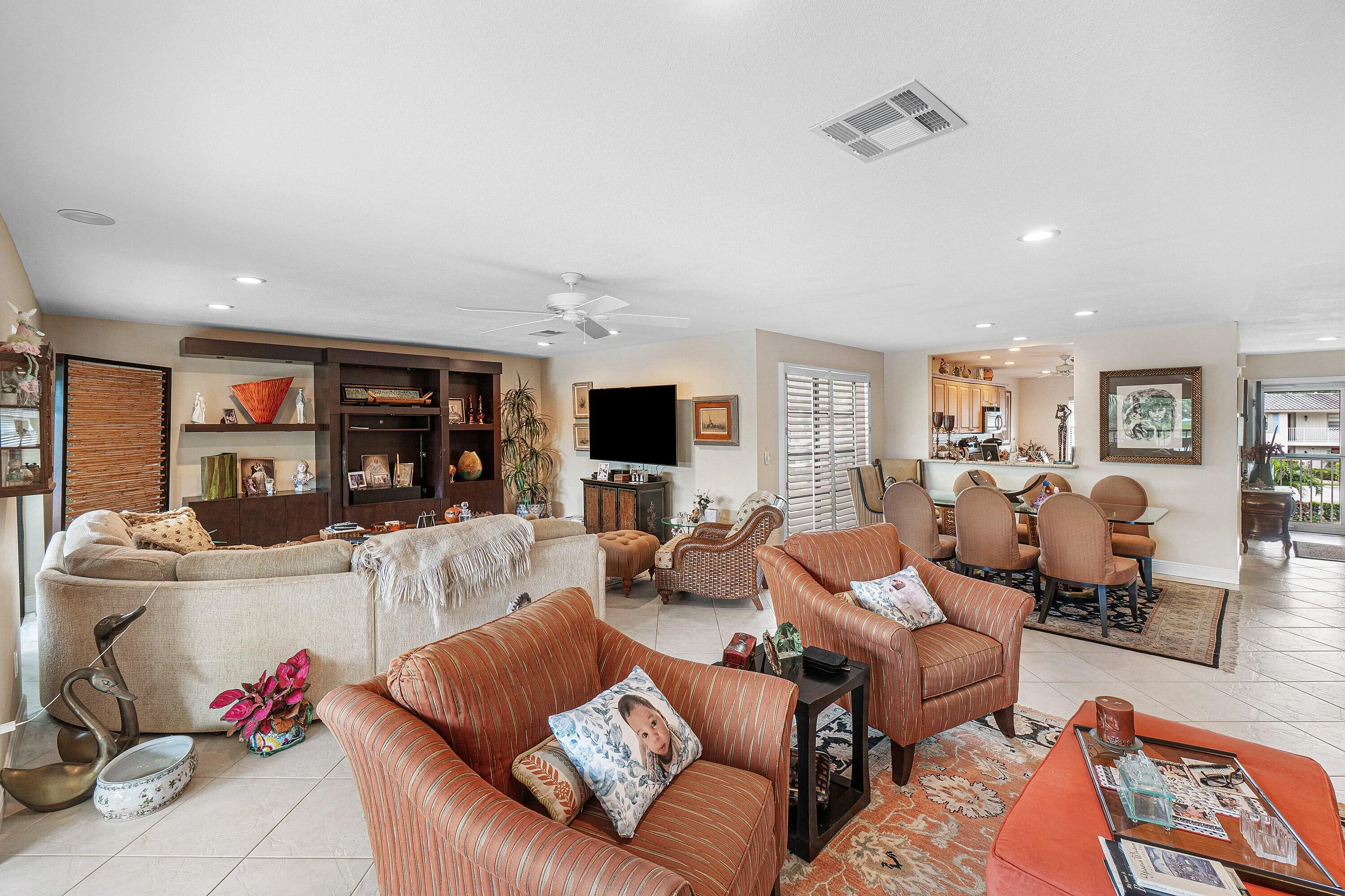 Spacious living area featuring tile flooring, recessed lighting, and a built-in entertainment center with open shelving