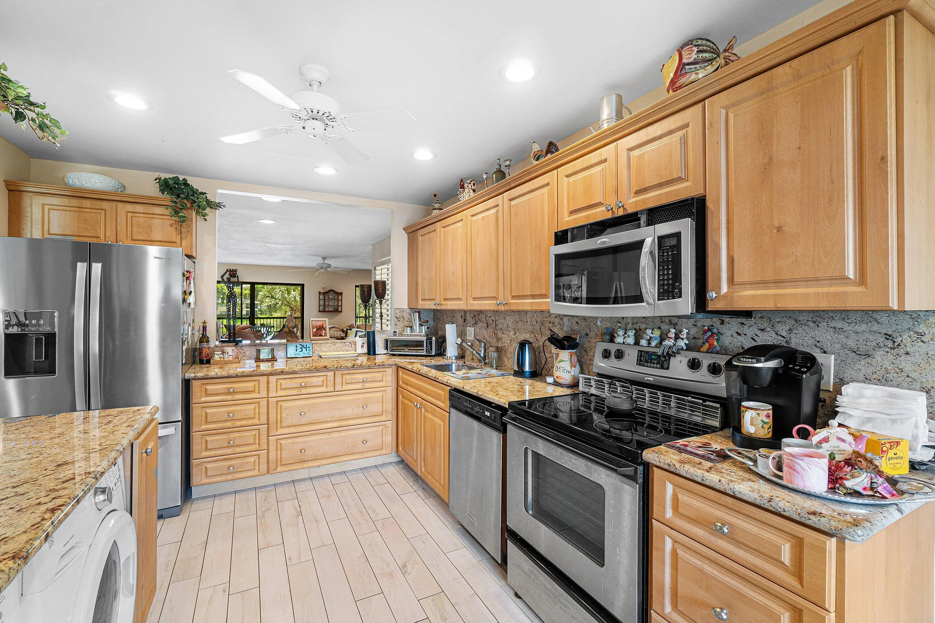 Kitchen featuring light wood cabinetry, granite countertops, tile flooring, and stainless steel appliances