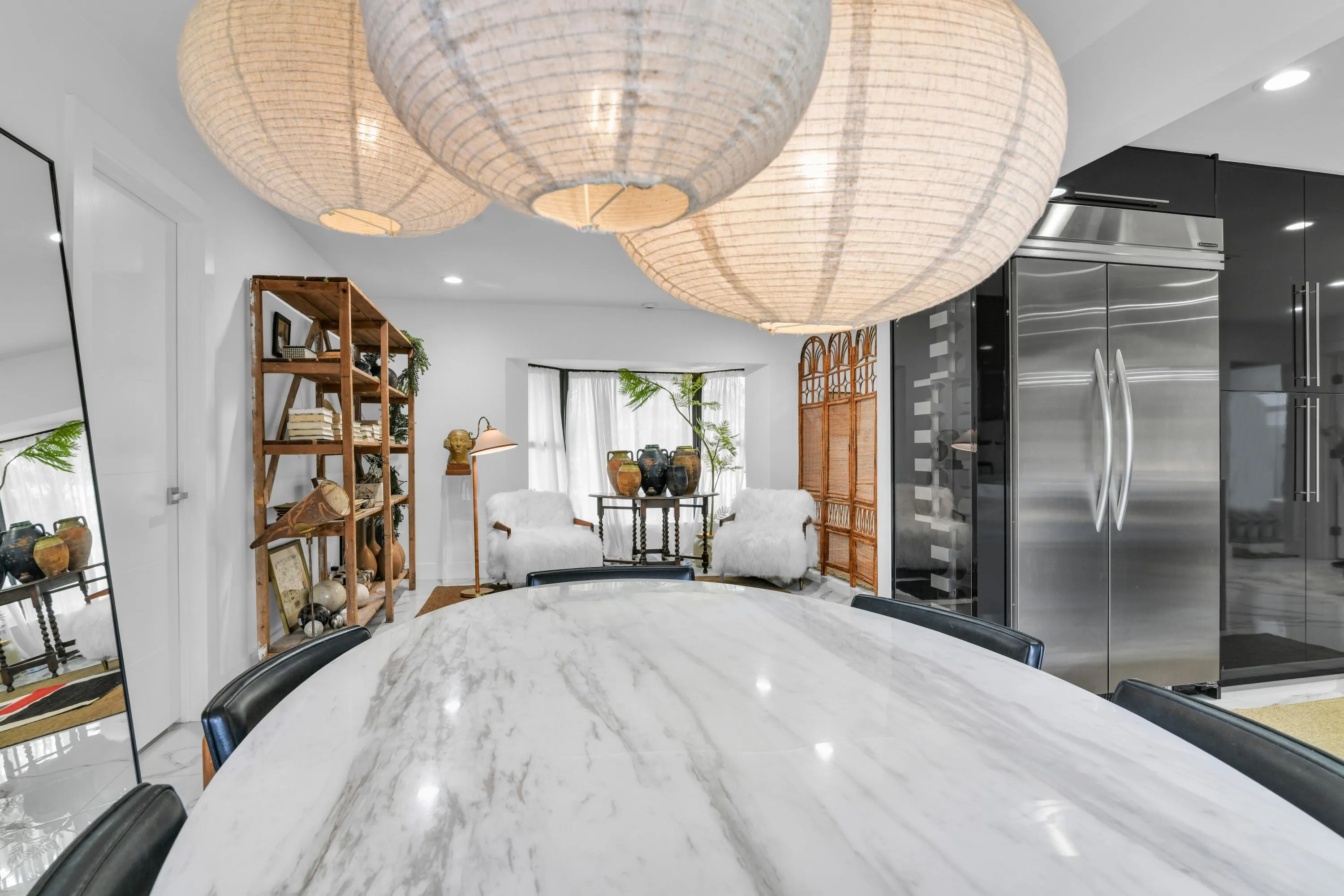 White marble-finish countertop, stainless steel refrigerator, built-in shelving, bay window, and contemporary pendant lighting