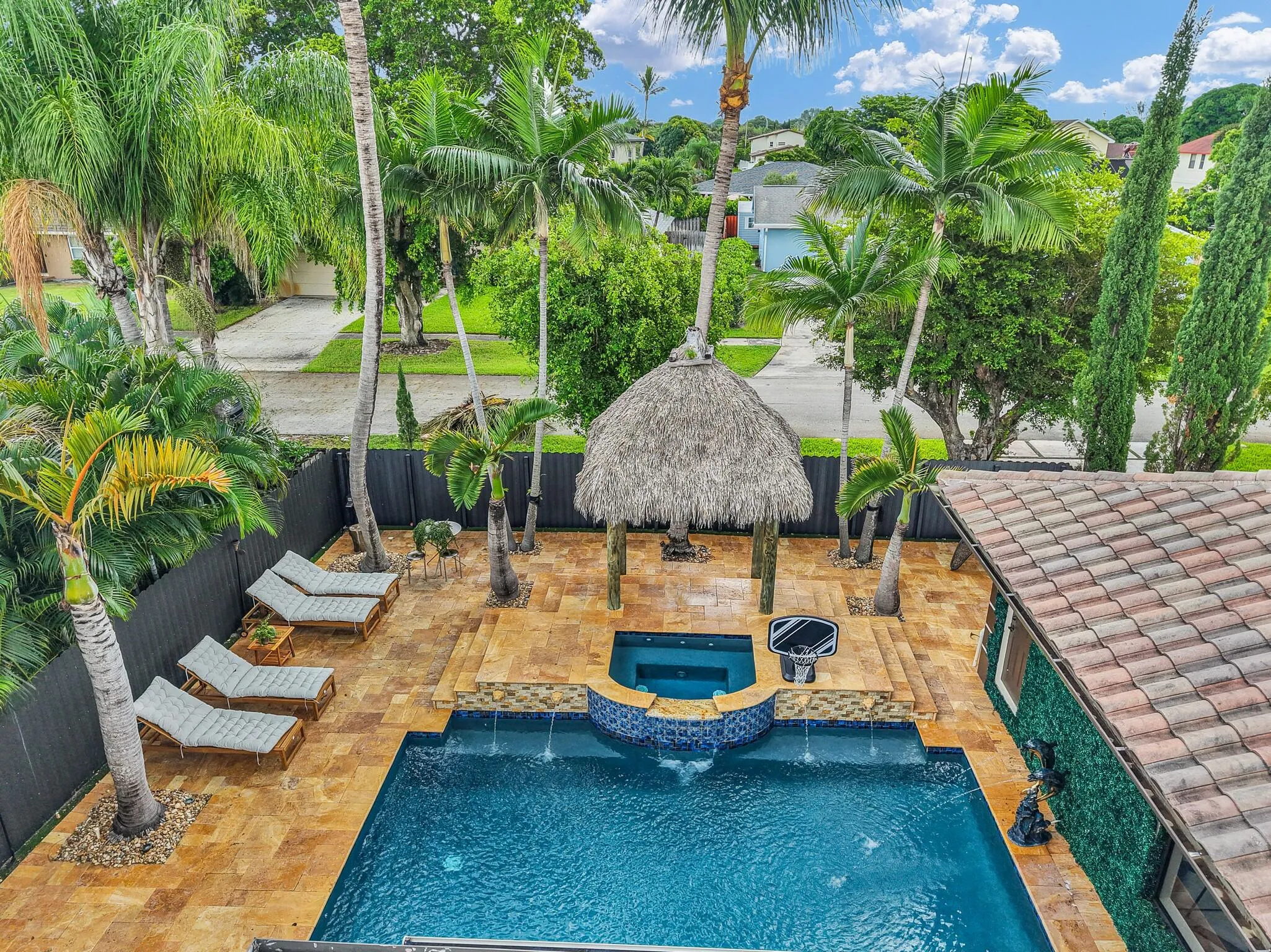 Lagoon-style swimming pool with water features, integrated spa, and an adjacent tiki hut