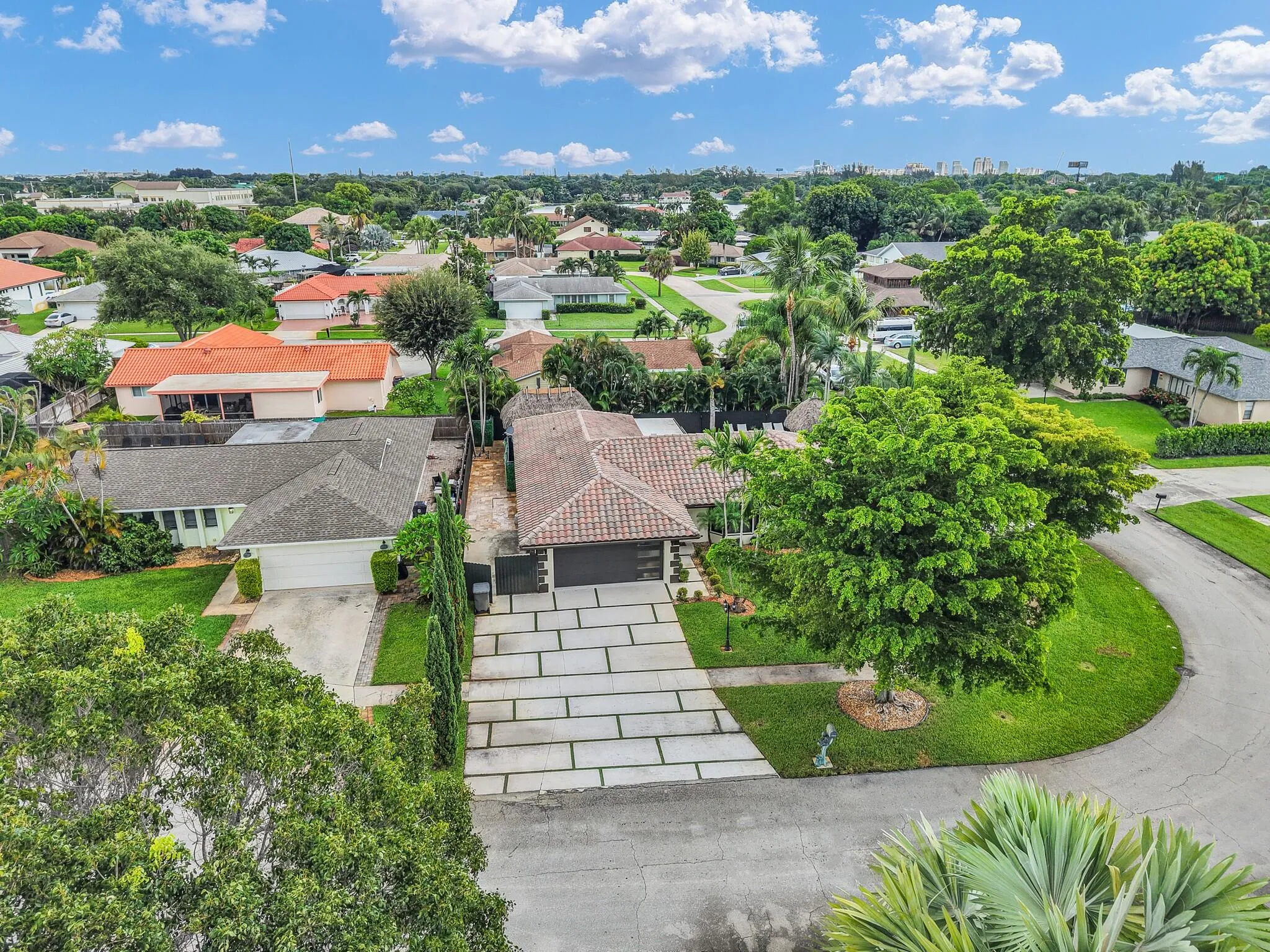 Aerial perspective of a single-story residence featuring a tile roof and a paver driveway