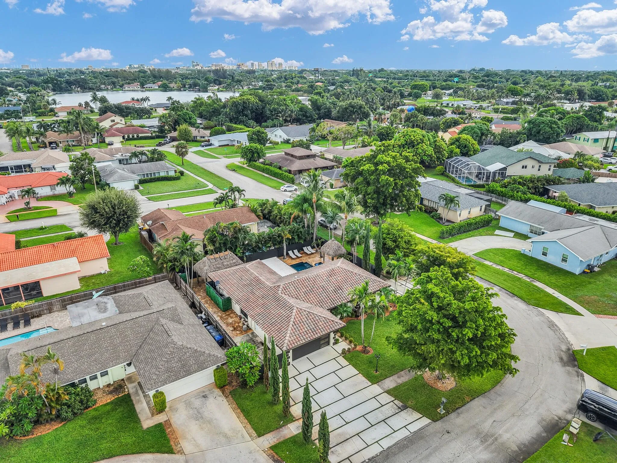 Aerial perspective of a neighborhood featuring a water body, mature landscaping, and a curvilinear street layout