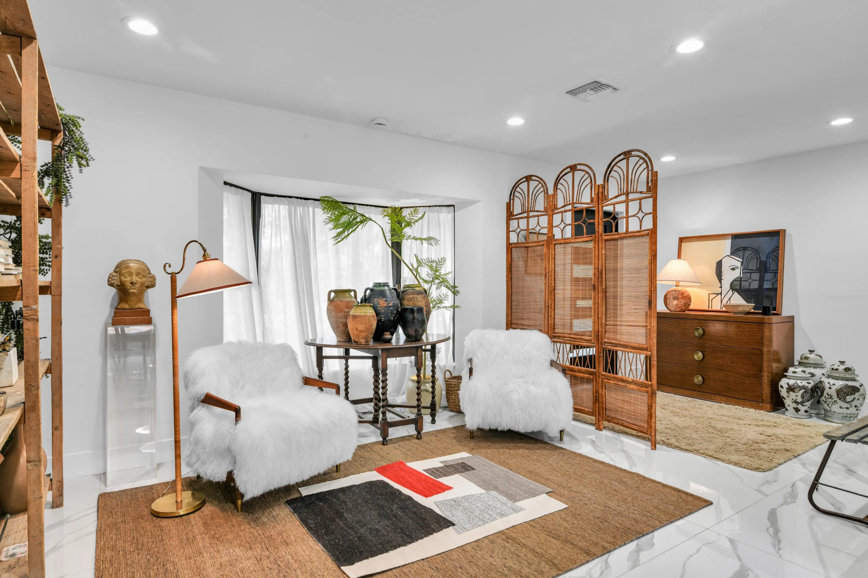 Recessed ceiling lighting, white walls, large bay window with white drapery, and polished tile flooring