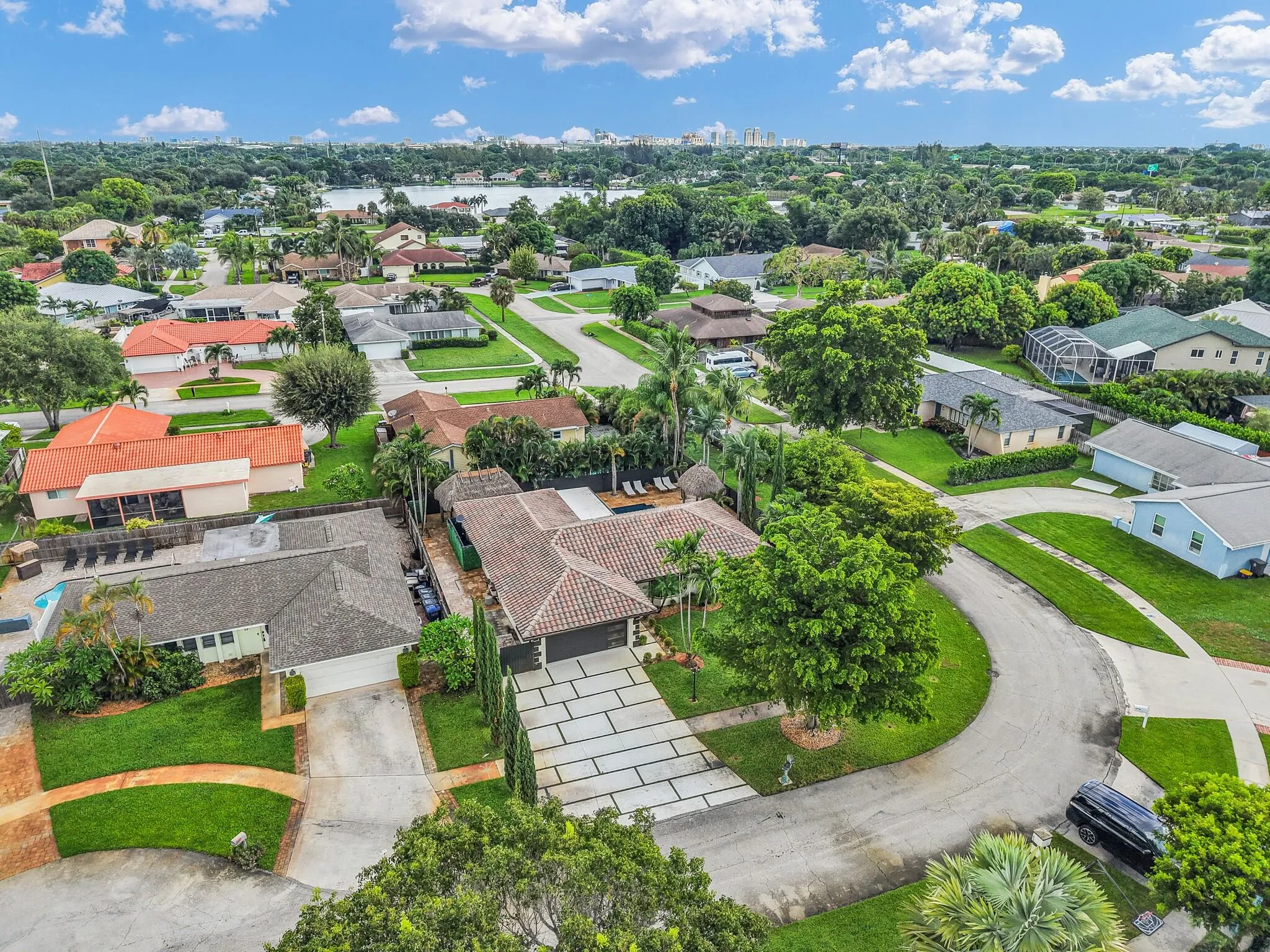 Expansive suburban neighborhood with mature trees, a curvilinear street layout, and a distant body of water