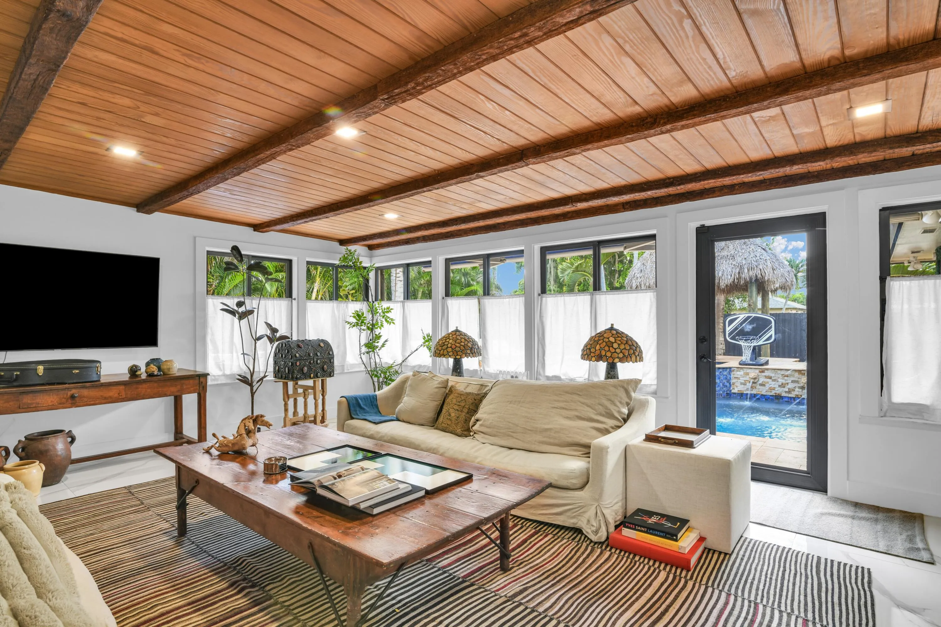 Wood-paneled ceiling with exposed beams, recessed lighting, and ample natural light through multiple windows