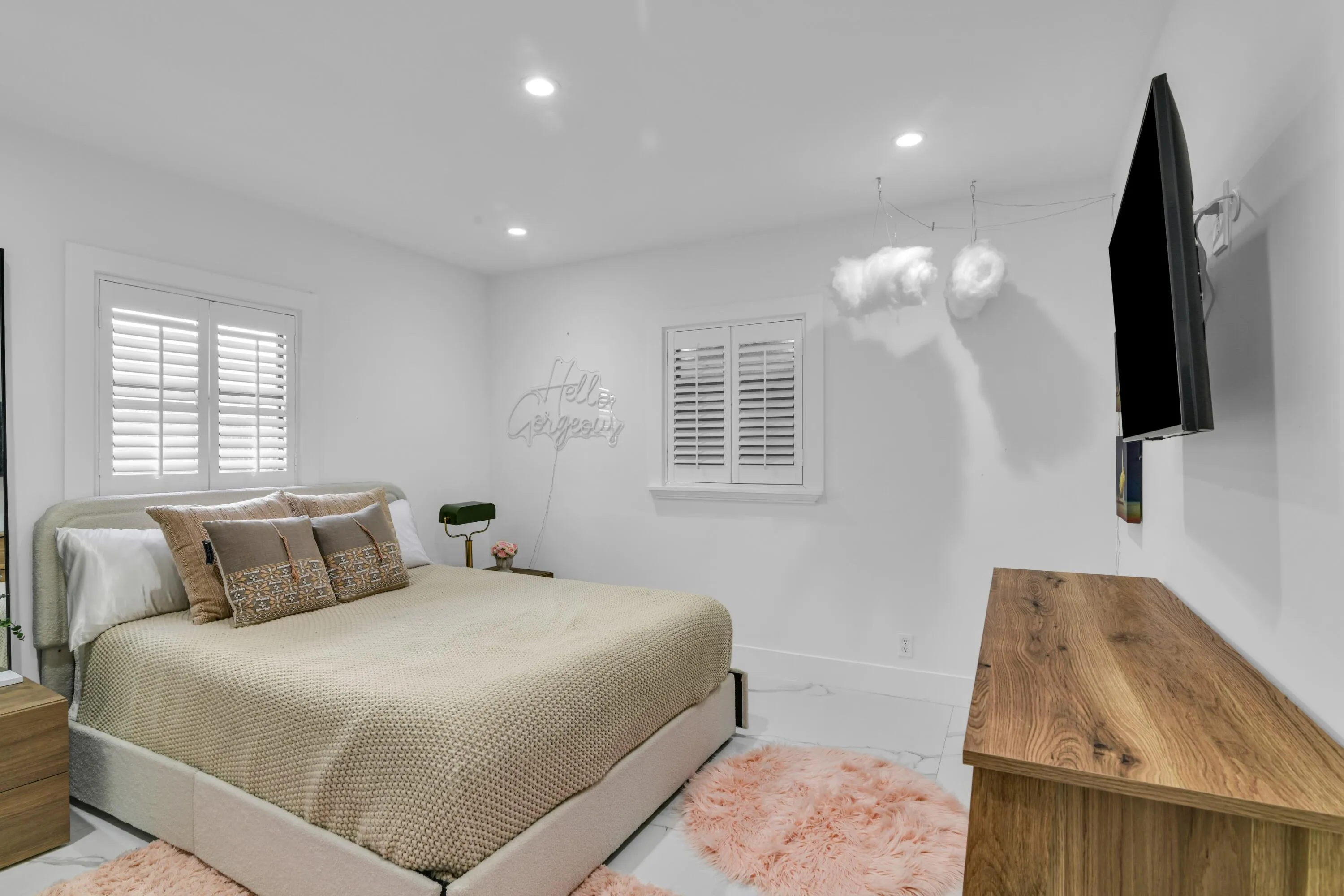 White plantation shutters, recessed lighting, wood-finish dresser, and light-tone flooring
