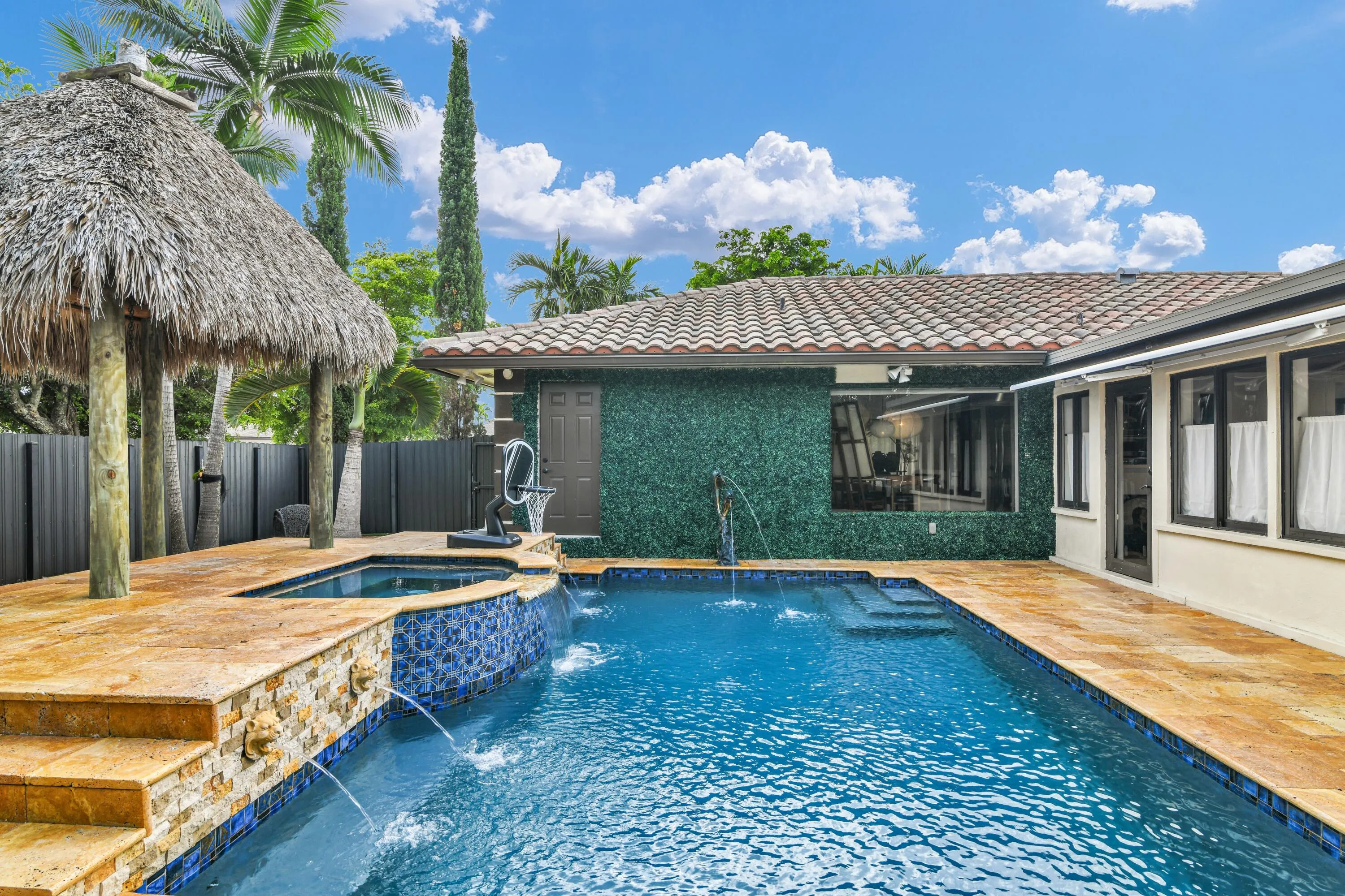 Swimming pool with integrated spa and water features, surrounded by a stone-tiled patio