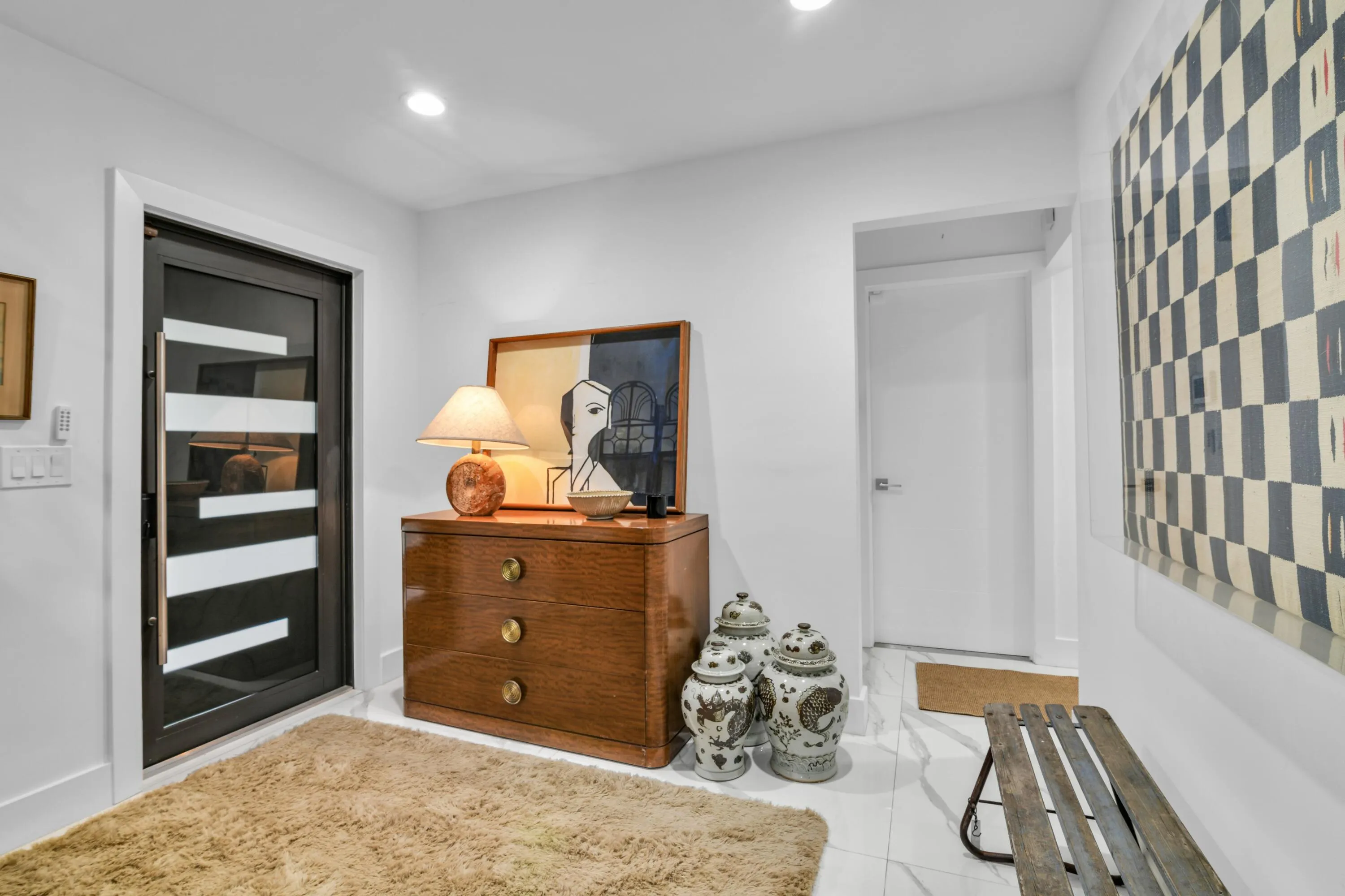 Modern entry door with horizontal frosted glass inserts, recessed lighting, and white wall finishes
