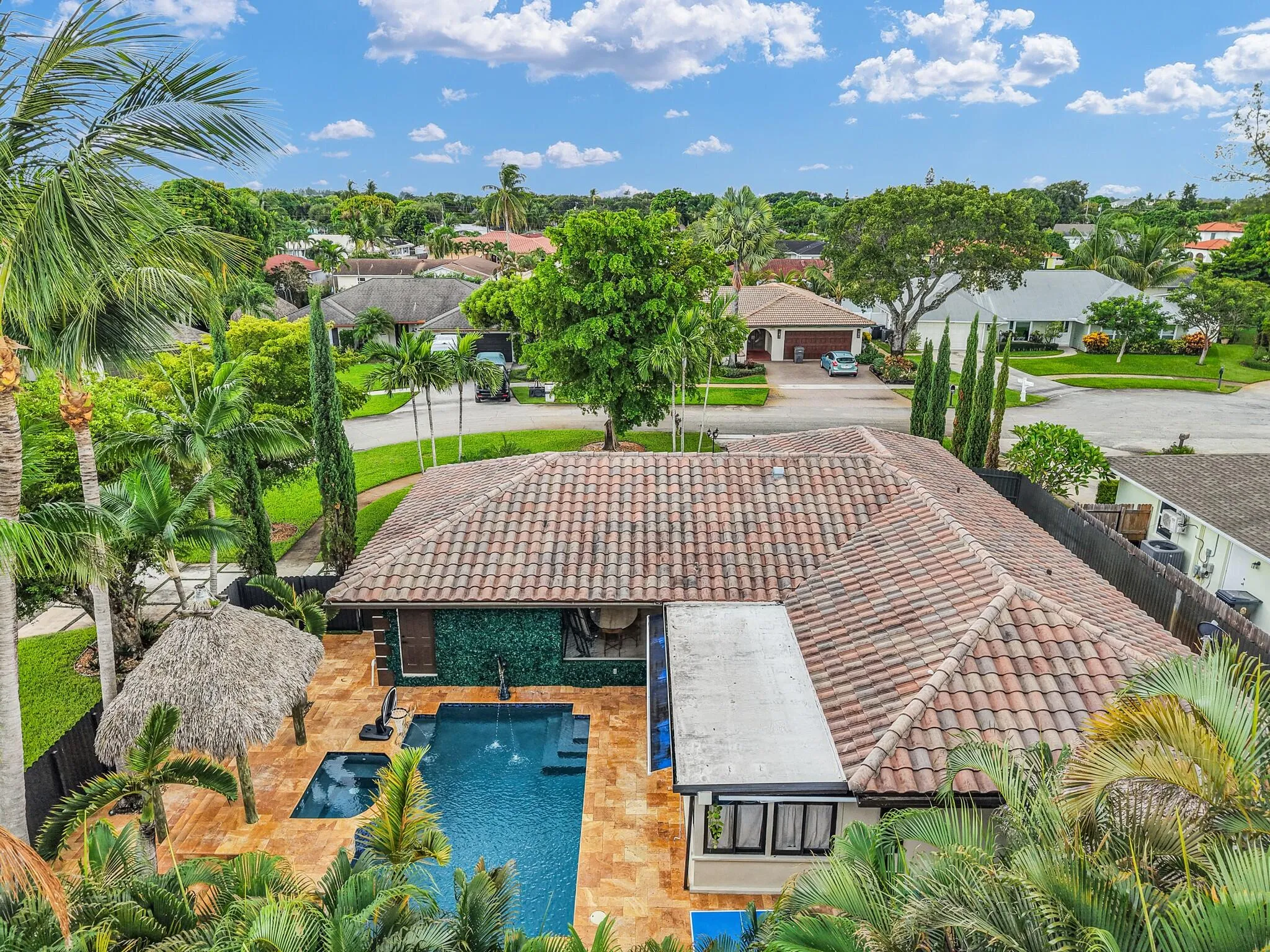 Terra cotta tile roof with a central swimming pool, integrated spa, and adjacent tiki hut