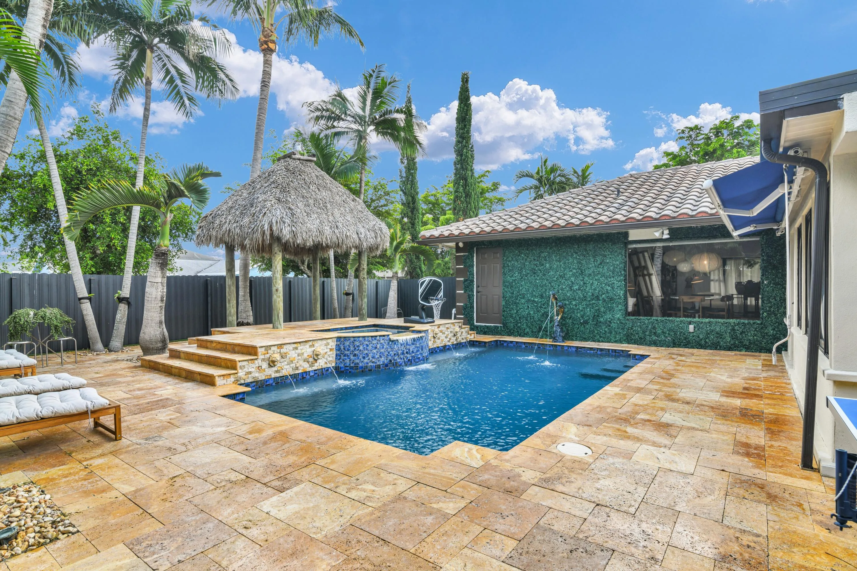 Swimming pool with integrated spa and water features, surrounded by extensive paver decking